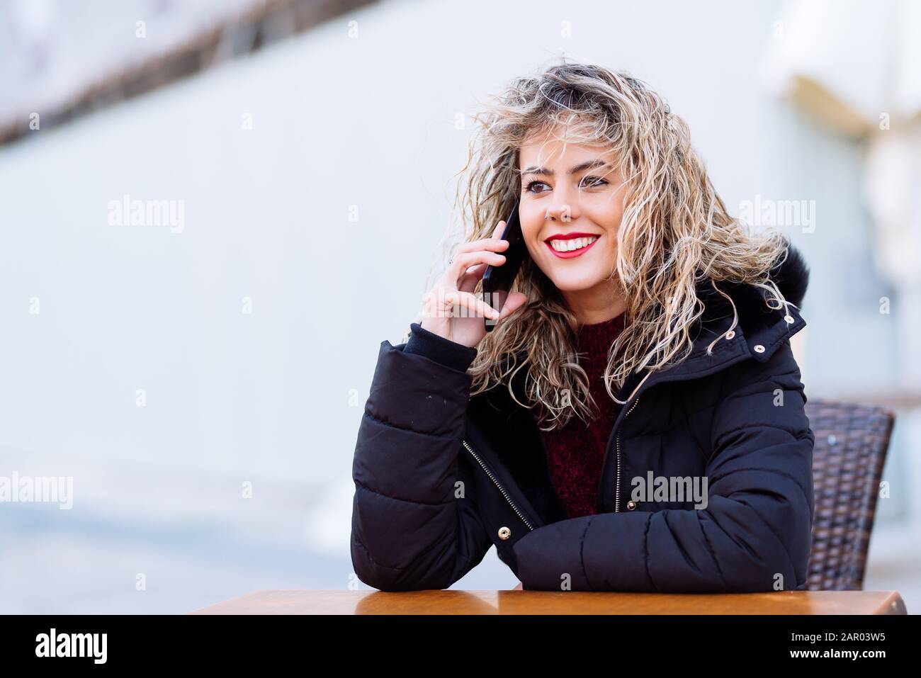 Bella cacuasia donna con smartphone. Capelli biondi ragazza ricci con spazio di copia per il testo Foto Stock