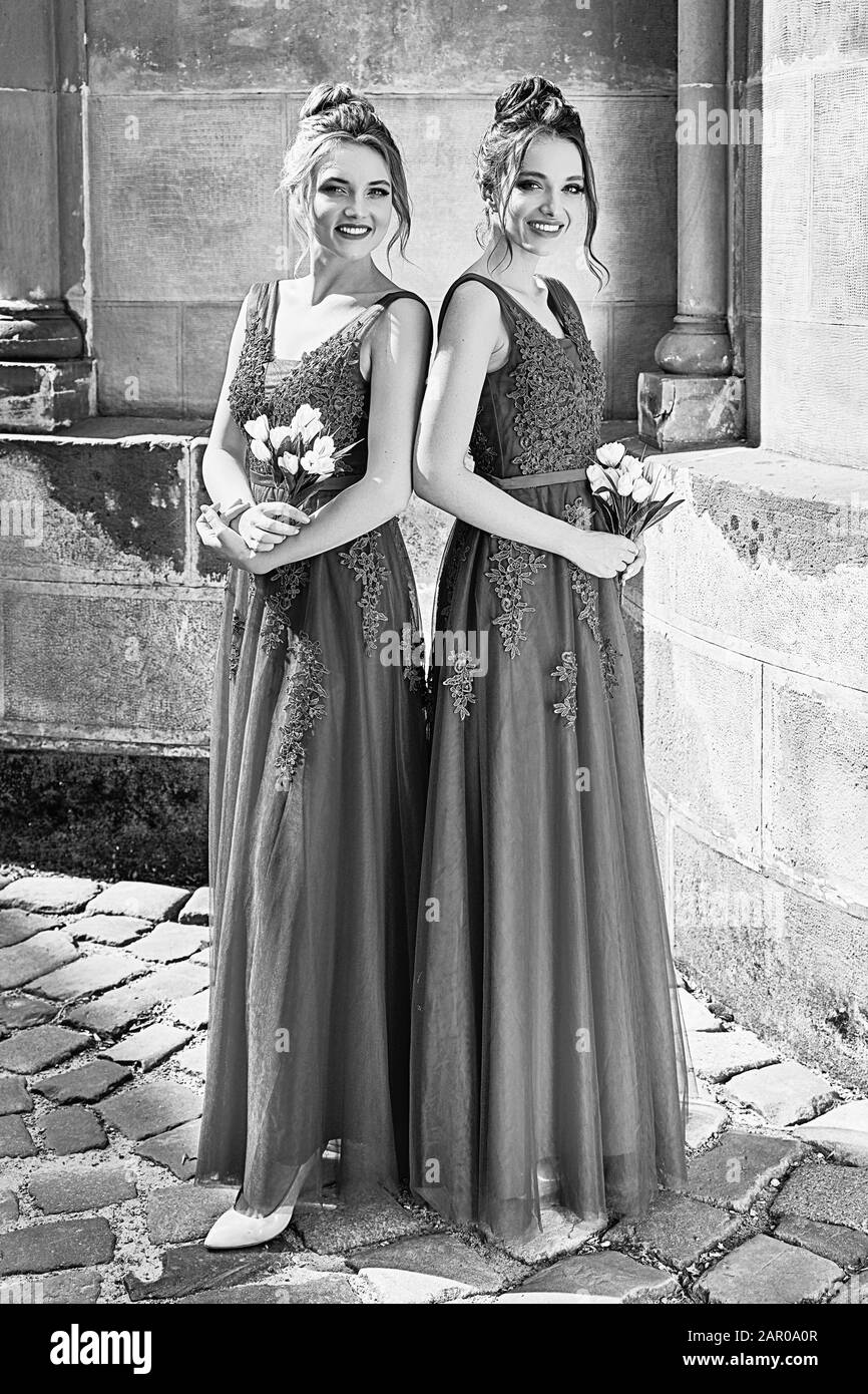 Due belle sposini ragazze bionde e donne brunette indossare elegante abito rosso chiffon bridesmaid a lunghezza intera con pizzo e fiore Foto Stock