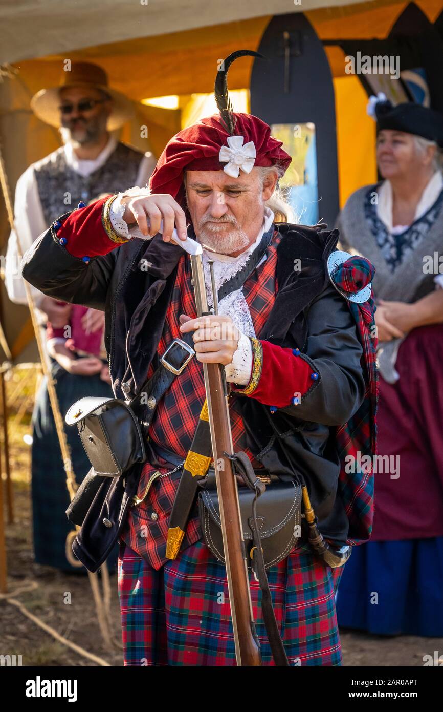 Membro del gruppo Scottish Living History nel vestito tradizionale dimostra il caricamento del fucile Flintlock al Glen Innes Celtic Festival NSW Foto Stock