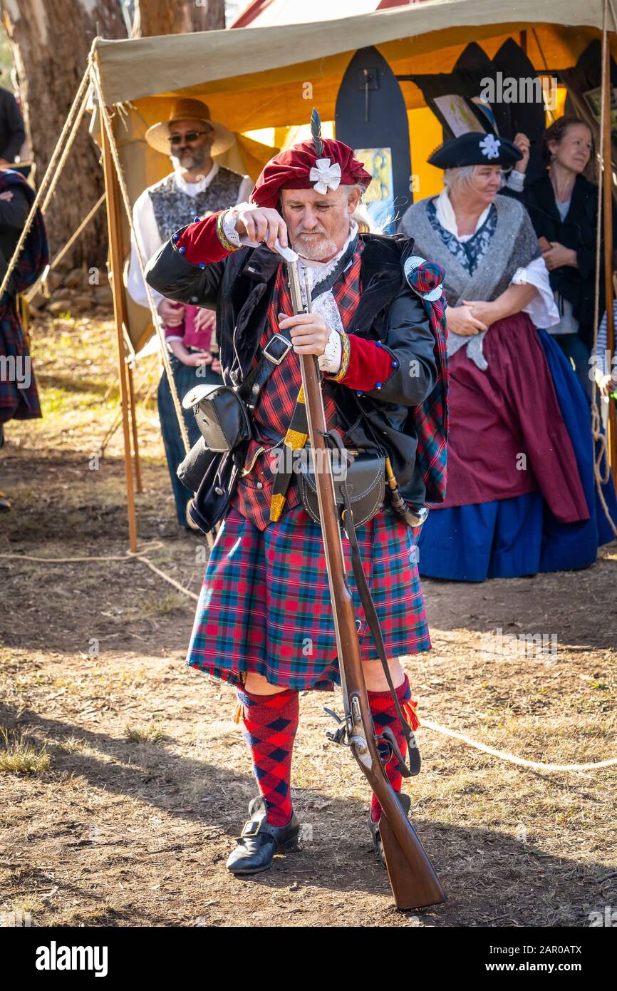 Membro del gruppo Scottish Living History nel vestito tradizionale dimostra il caricamento del fucile Flintlock al Glen Innes Celtic Festival NSW Foto Stock