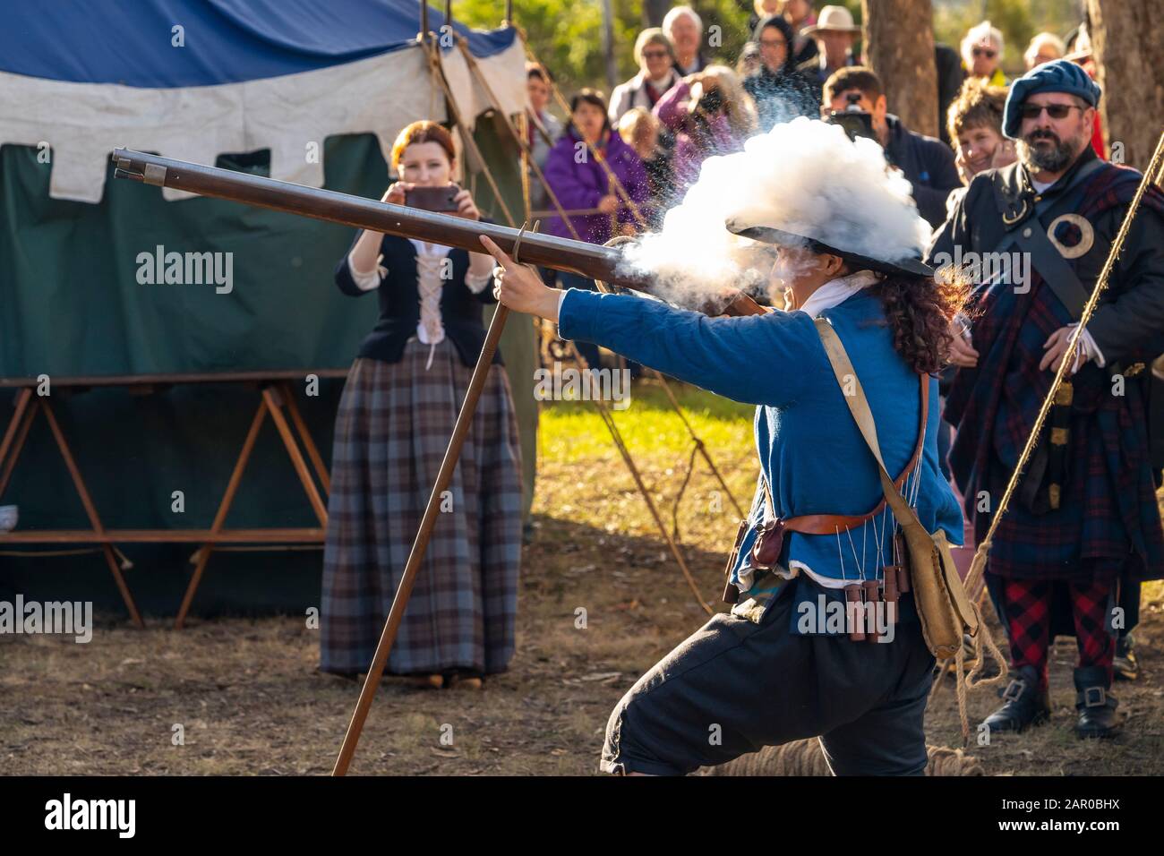 Membro del gruppo Scottish Living History nel vestito tradizionale dimostra il caricamento e la spara del fucile Flintlock al Glen Innes Celtic Festival NSW Foto Stock