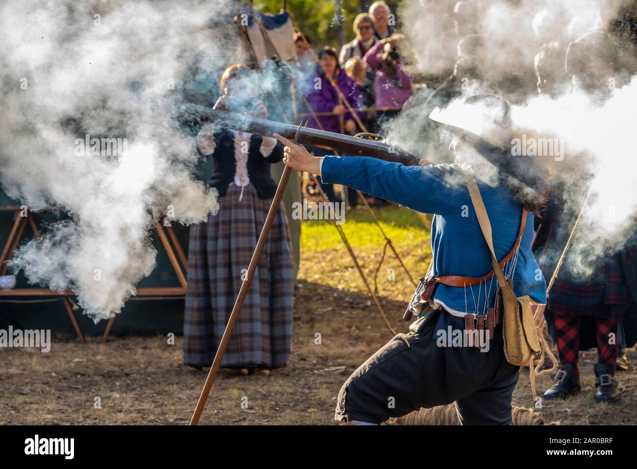 Membro del gruppo Scottish Living History nel vestito tradizionale dimostra il caricamento e la spara del fucile Flintlock al Glen Innes Celtic Festival NSW Foto Stock