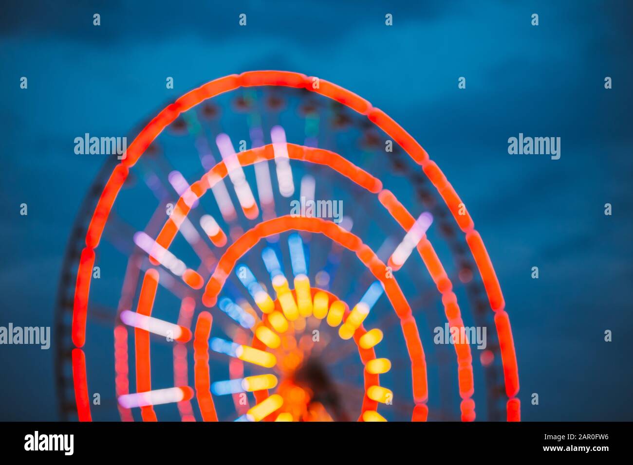 Sfocatura Astratta Di Ruota Panoramica Illuminata Dai Colori Vivaci Nel Parco Divertimenti Della Città. Bokeh Boke Sfondo. Foto Stock