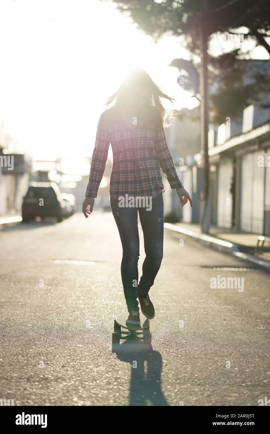 Ragazza a bordo di una longboard al tramonto Foto Stock