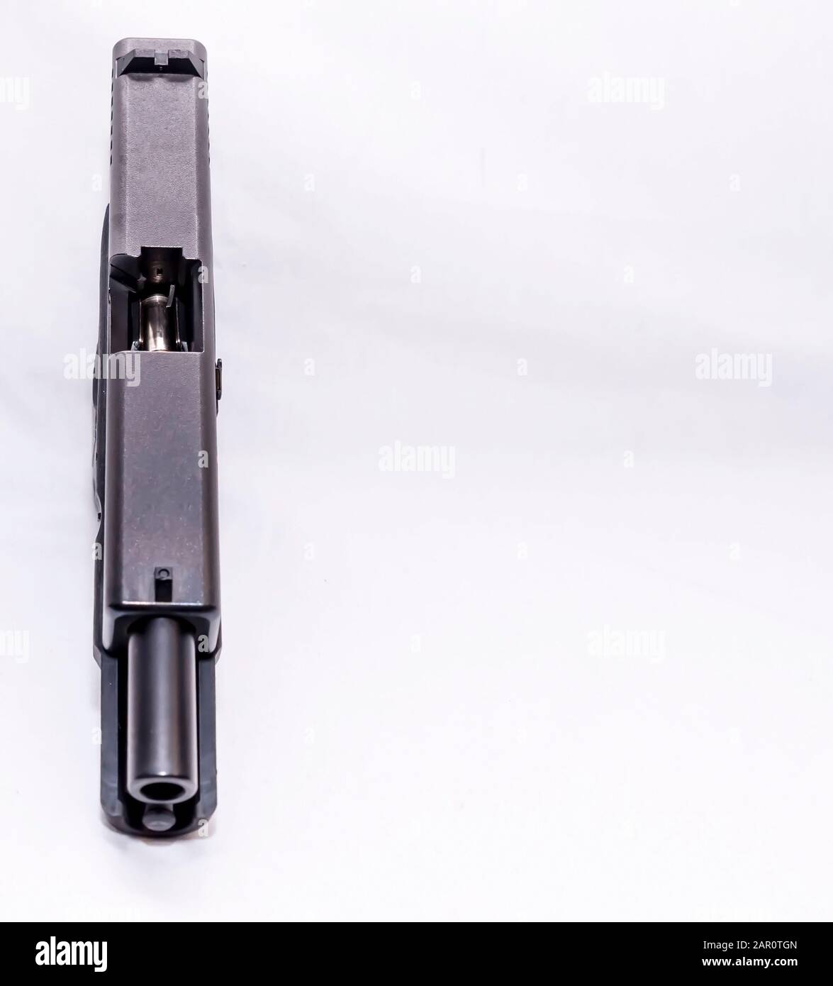 Una pistola semi-automatica 9mm nera con una slitta aperta che mostra un proiettile nella rivista su uno sfondo bianco con spazio di copia Foto Stock