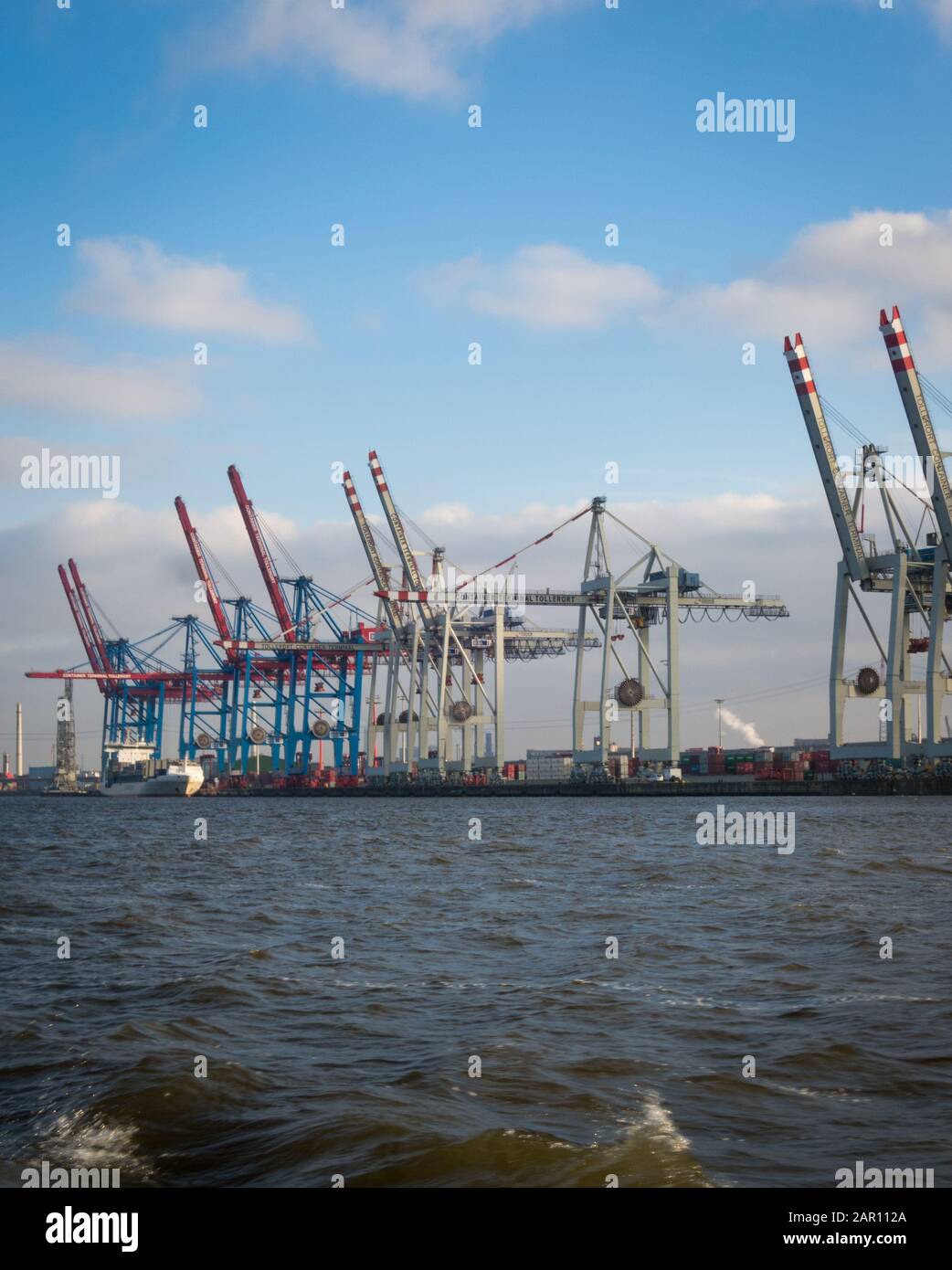 Le gru del porto di Amburgo attraccano i container delle navi da carico nelle giornate di sole. Nessuna gente visibile, fiume Elba di fronte. CopySpace disponibile Foto Stock