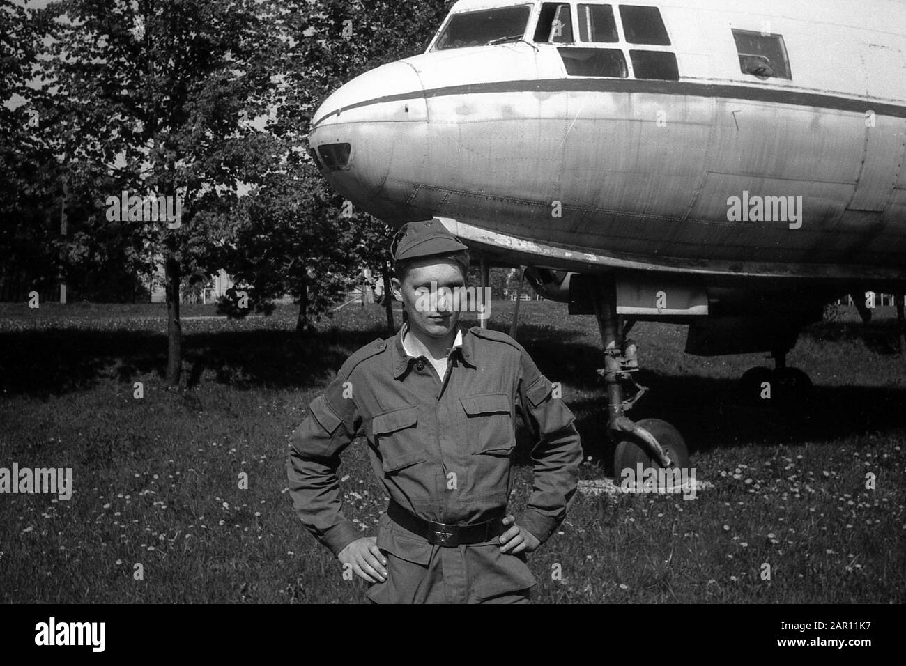 Stupino, REGIONE DI MOSCA, RUSSIA - CIRCA 1992: Un soldato dell'esercito russo sullo sfondo di un aereo militare sovietico a doppio motore per il trasporto del carico Ilyushin il-14. Bianco e nero. Scansione su pellicola. Grano grande. Foto Stock