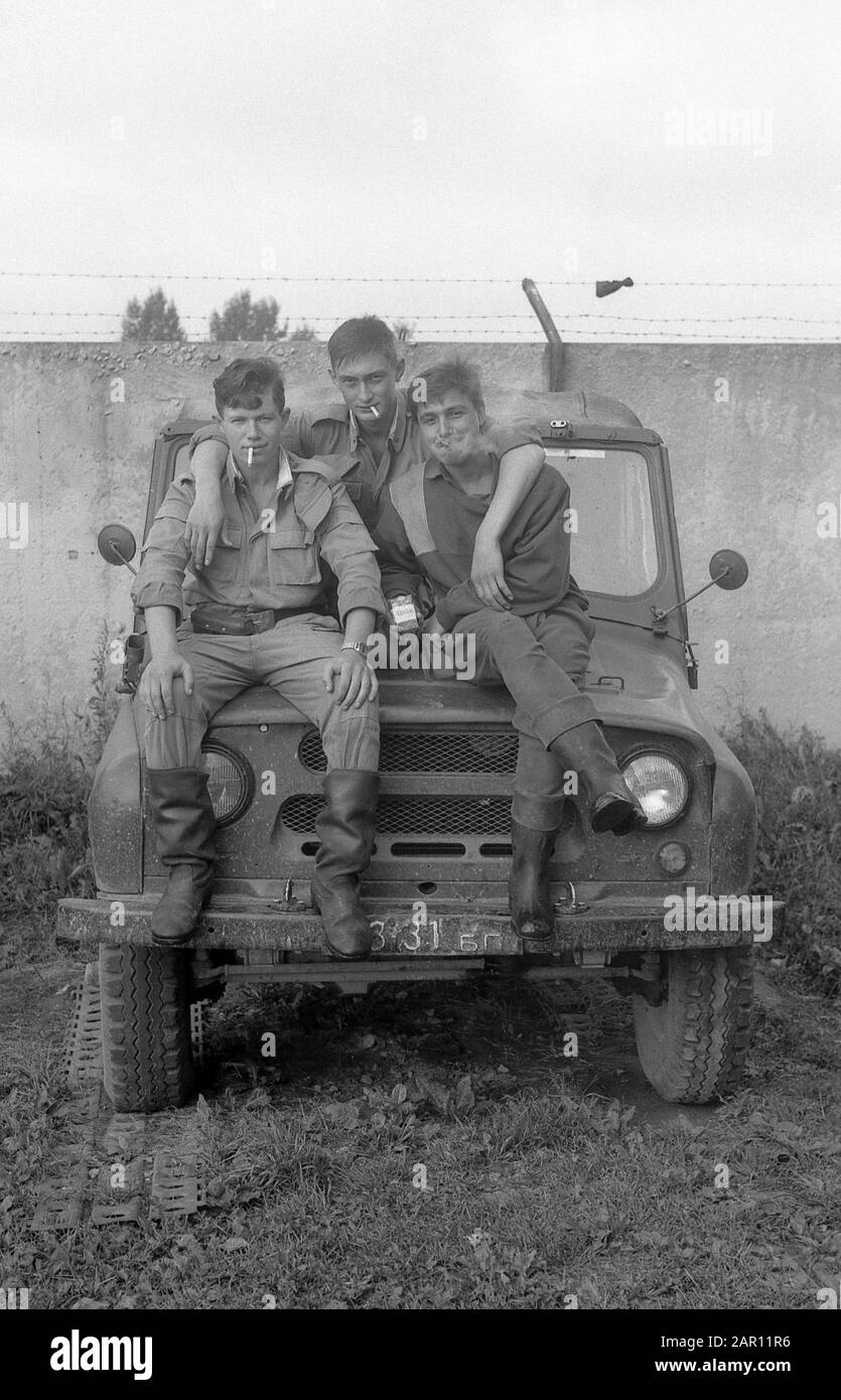 Stupino, REGIONE DI MOSCA, RUSSIA - CIRCA 1993: I Tre Compagni, i soldati russi dell'esercito siedono sulla cappa di un SUV UAZ. Bianco e nero. Scansione su pellicola. Grano grande. Foto Stock