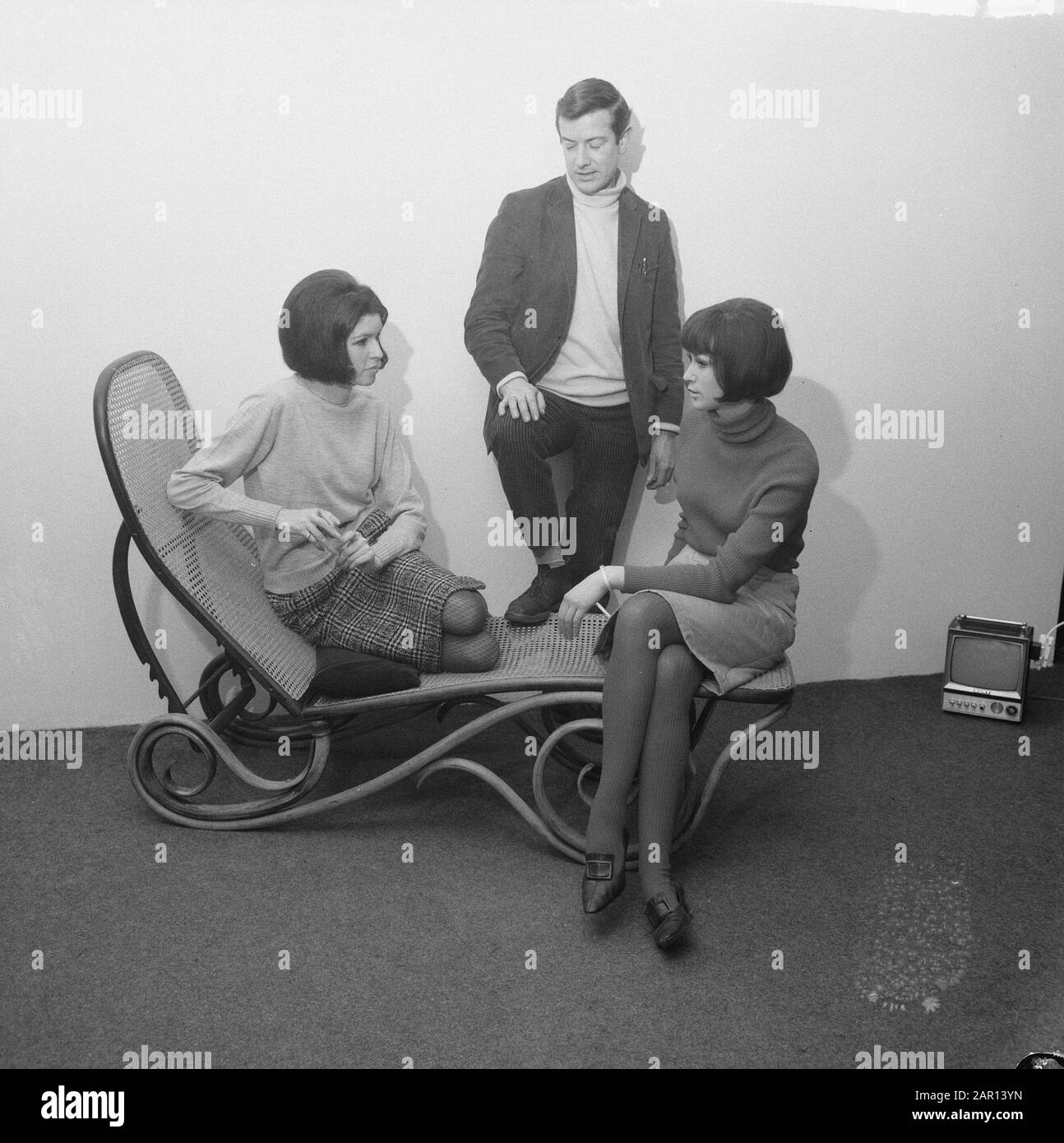 Task Telegraph Annotation: Due giovani donne con turtlenecks e gonne su un lettino in vimini nel mezzo un uomo nel dolcevita. Sulla destra si può vedere una mini televisione Data: 28 gennaio 1965 Nome dell'istituzione: Telegraph Foto Stock