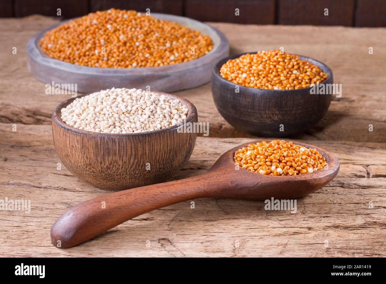 Semi di quinoa e miglio rosso in ciotola su legno rustico Foto Stock