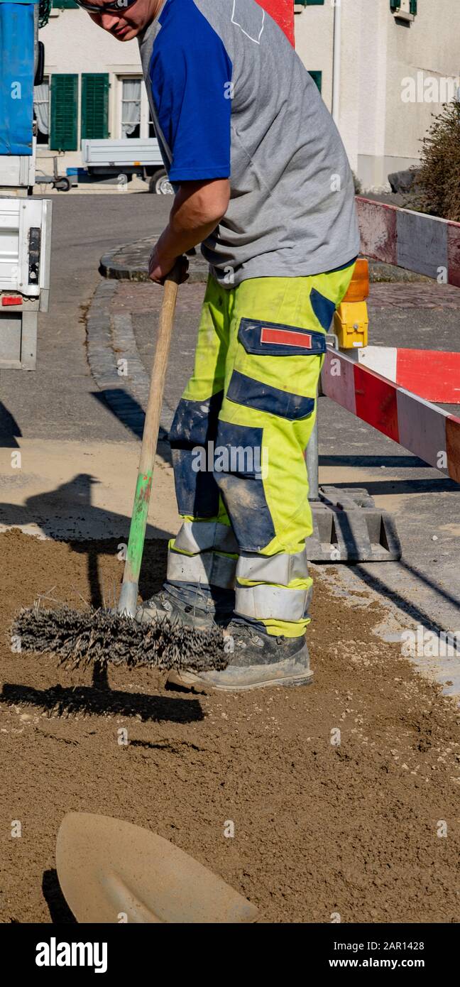 Tubazioni meccanico scrubbing sabbia in cantiere di fronte a un veicolo da costruzione e rimorchio con pala in primo piano. Oleodotto meccanico; bro Foto Stock