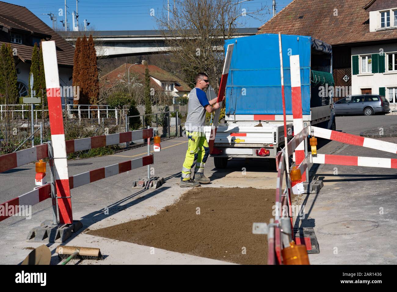 Giovani operai di costruzione sta eliminando le barriere di un constructon sulla strada. Scopa di strada; radendo via; scopa per costruzione di strada; scrube Foto Stock