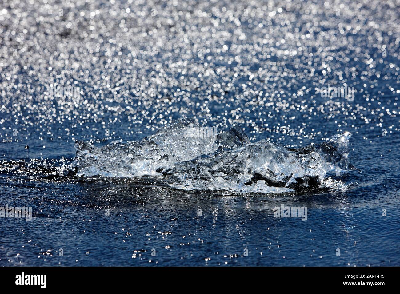 i resti di un iceberg brillano alla luce del sole mentre si lava su jokulsarlon spiaggia islanda Foto Stock