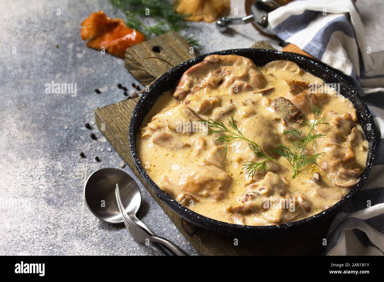 Fricasse - Cucina Francese. Pollo stufato in salsa cremosa con funghi in una padella su uno sfondo di pietra leggera. Foto Stock