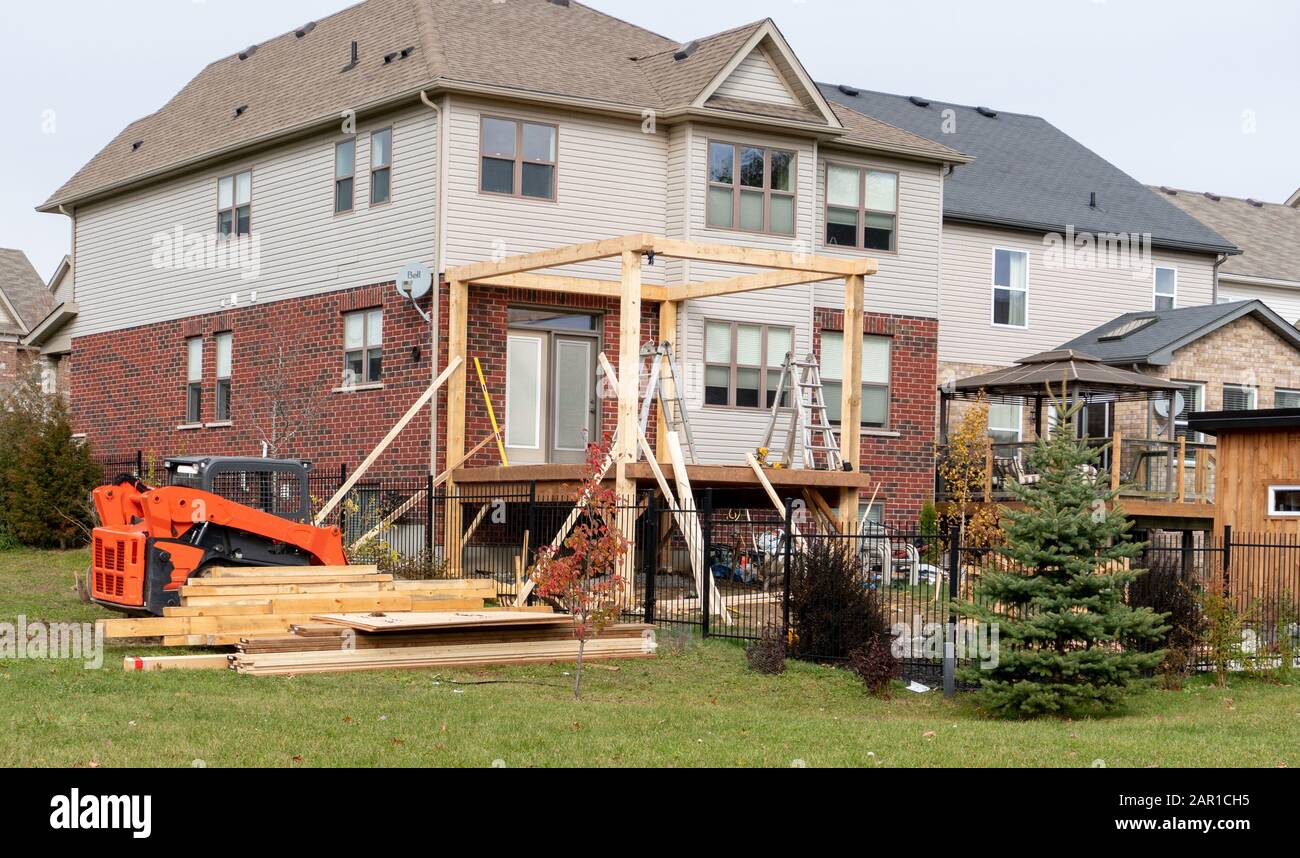 Costruzione di una veranda in legno con tetto nel processo installato puntelli e il trattore ha scaricato nuove tavole Foto Stock