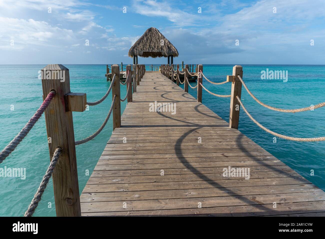 Un lungo ponte di legno conduce al mare fino alla terrazza di osservazione con un baldacchino di legno di foglie di palma Foto Stock