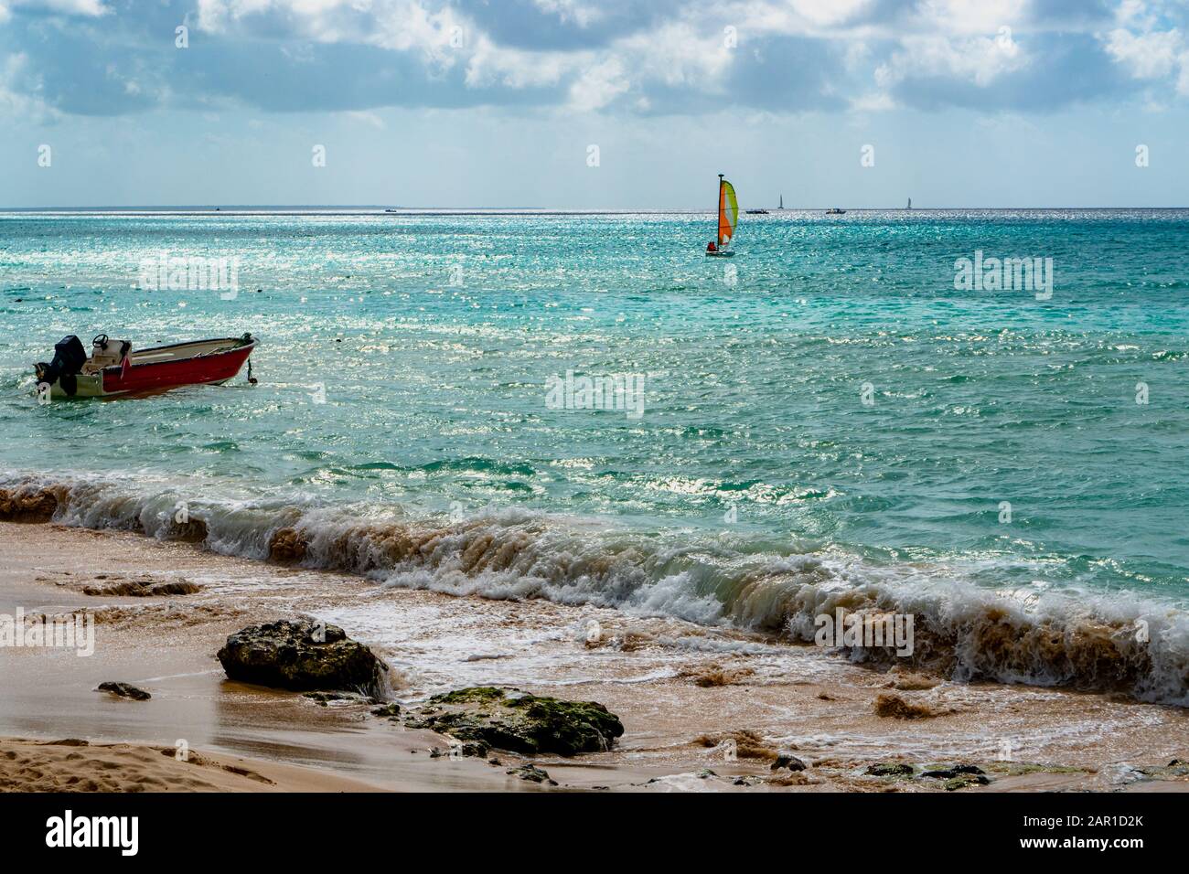 Vista mare con onde che corrono a terra e con barche e barche a vela all'orizzonte Foto Stock