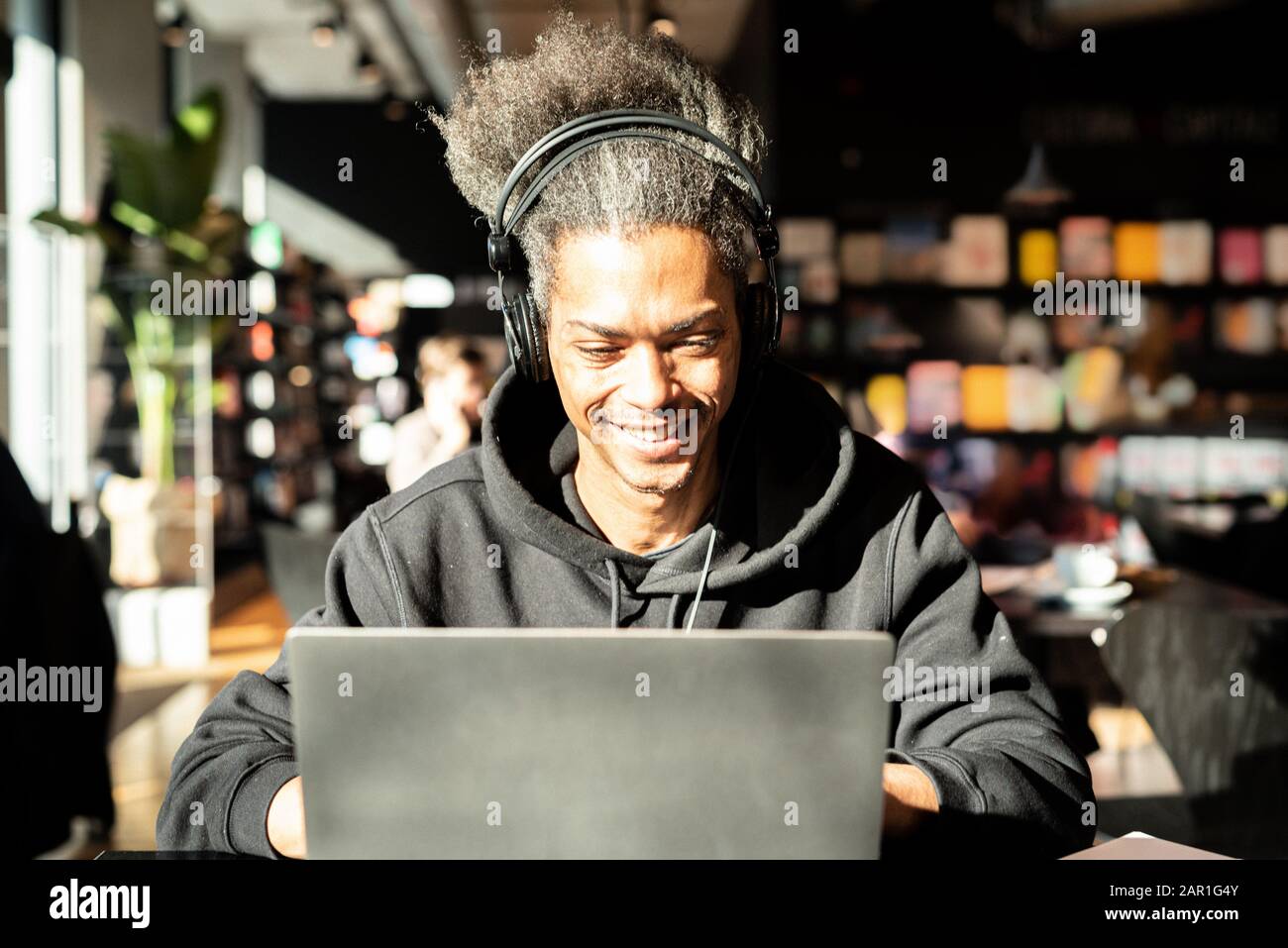 giovane afroamericano è in connessione con una videochiamata, giovane latinoamericano guardare contenuti multimediali, sta navigando in internet alla ricerca di nuovo blo Foto Stock