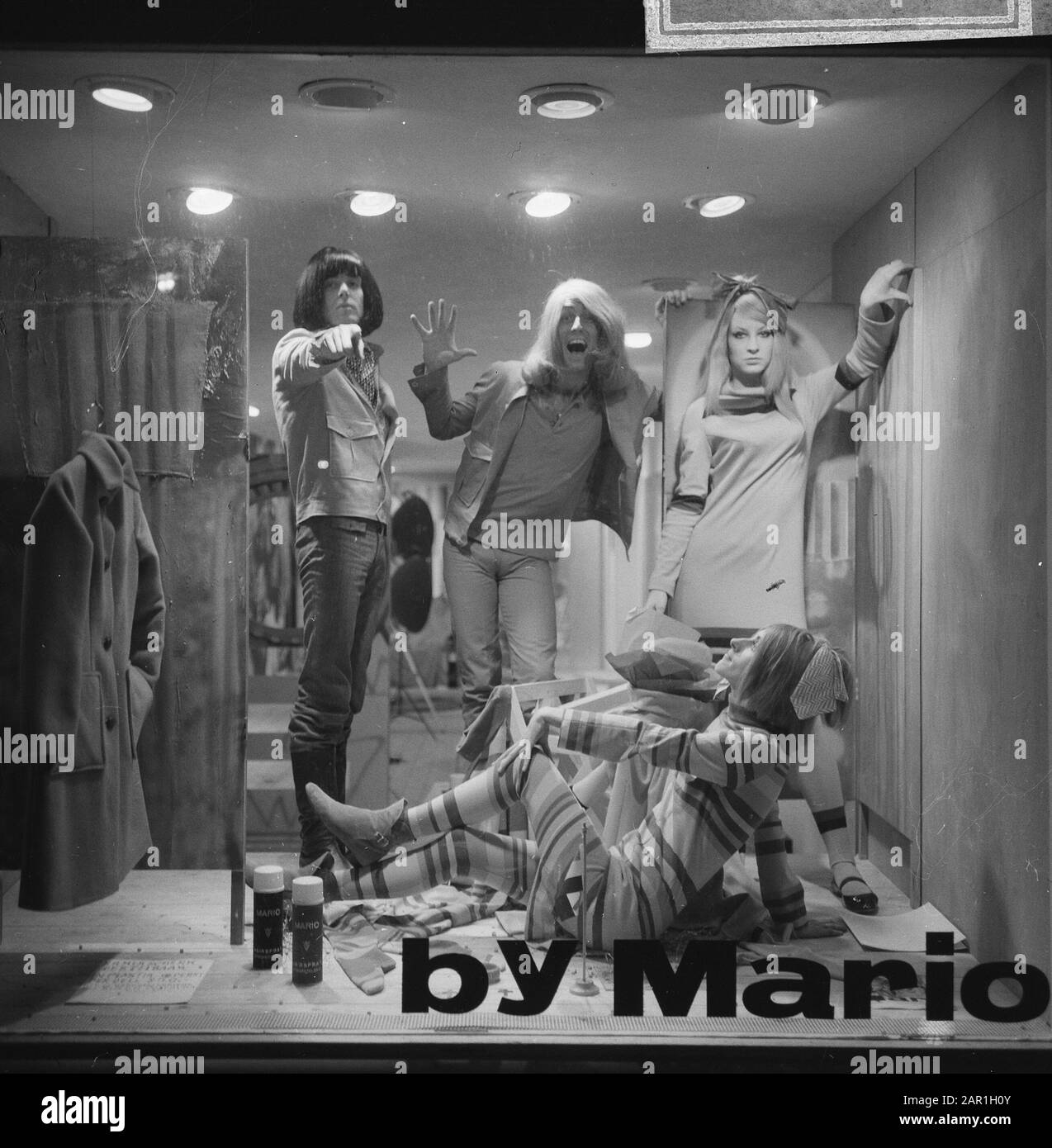 Parrucchiere Mario, titolare del parrucchiere The Trend di Amsterdam, con parrucca Mario e pittore Simon Postuma (con parrucche) mentre si posa in vetrina, insieme a due modelli Data: 5 novembre 1965 luogo: Amsterdam, Noord-Holland Parole Chiave: Modelli fotografici, parrucchieri, pittori, moda, parrucche Nome personale: Postuma, Simon Foto Stock