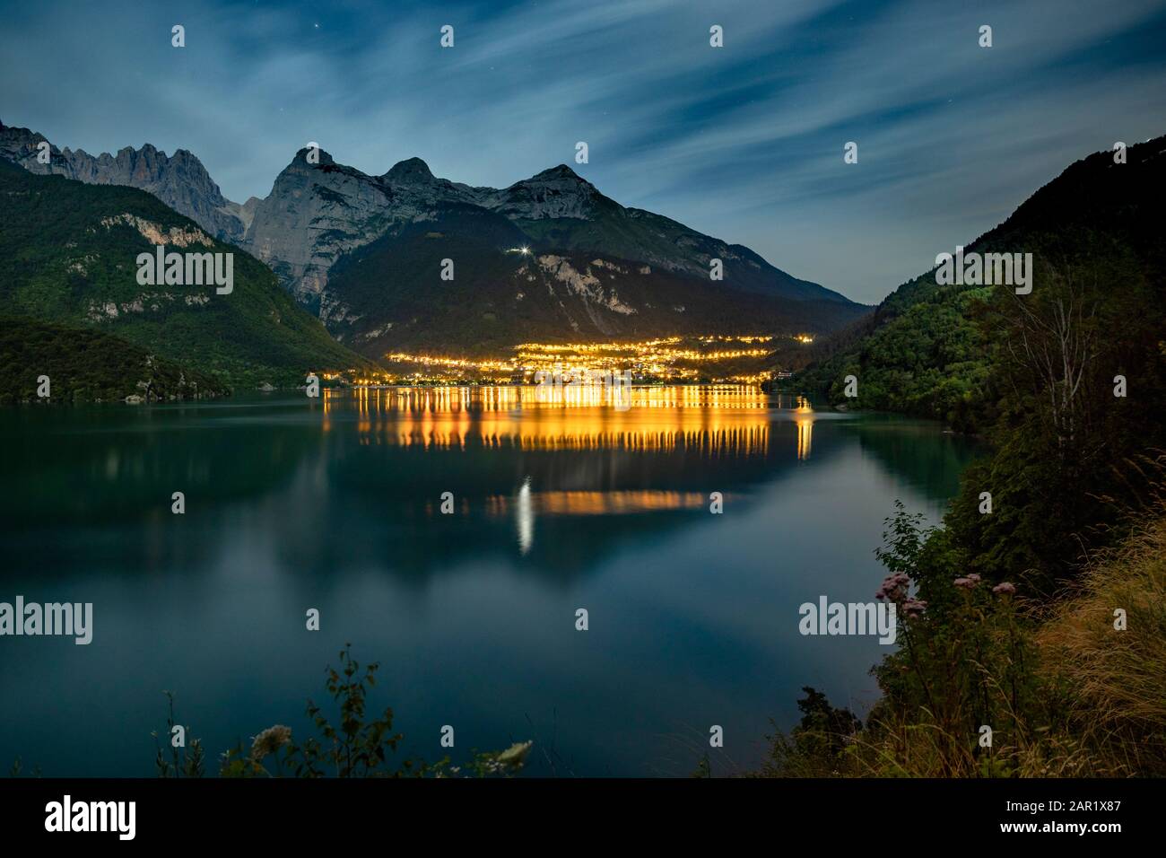 Il bellissimo Molveno di notte con la luce riflessa sul grande lago. Sullo sfondo ci sono grandi montagne Foto Stock