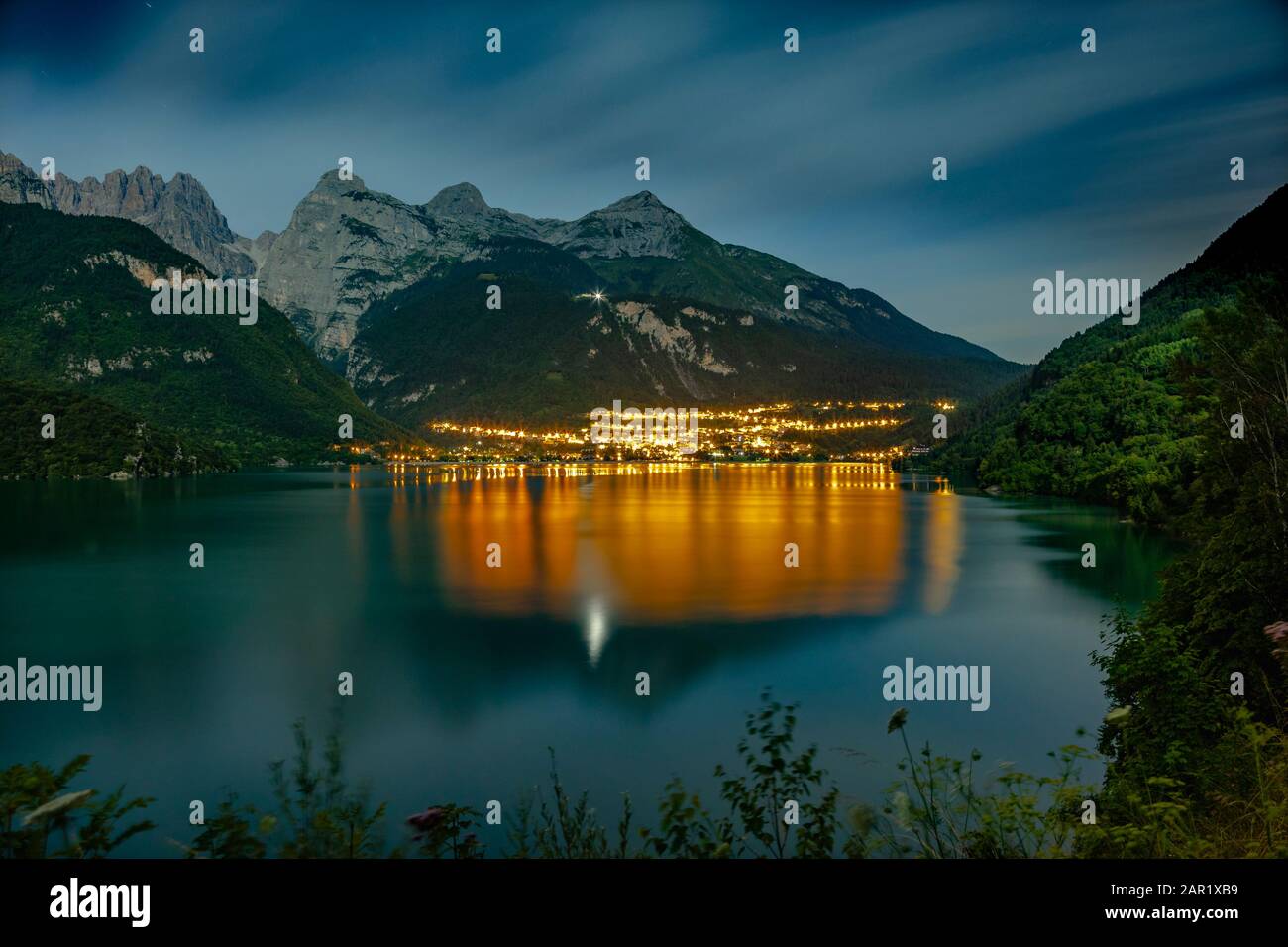 Il bellissimo Molveno di notte con la luce riflessa sul grande lago. Sullo sfondo ci sono grandi montagne Foto Stock