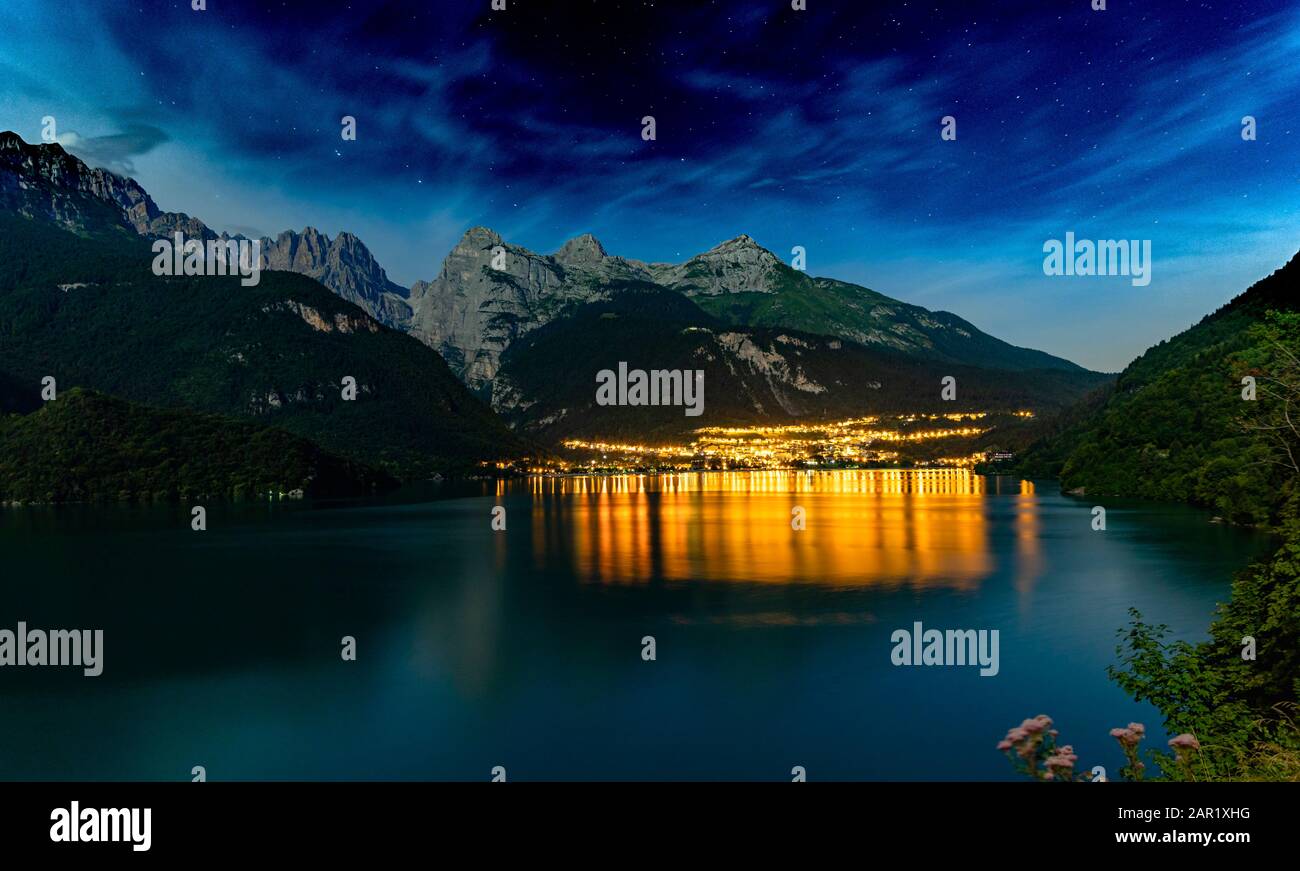 Il bellissimo Molveno di notte con la luce riflessa sul grande lago. Sullo sfondo ci sono grandi montagne Foto Stock