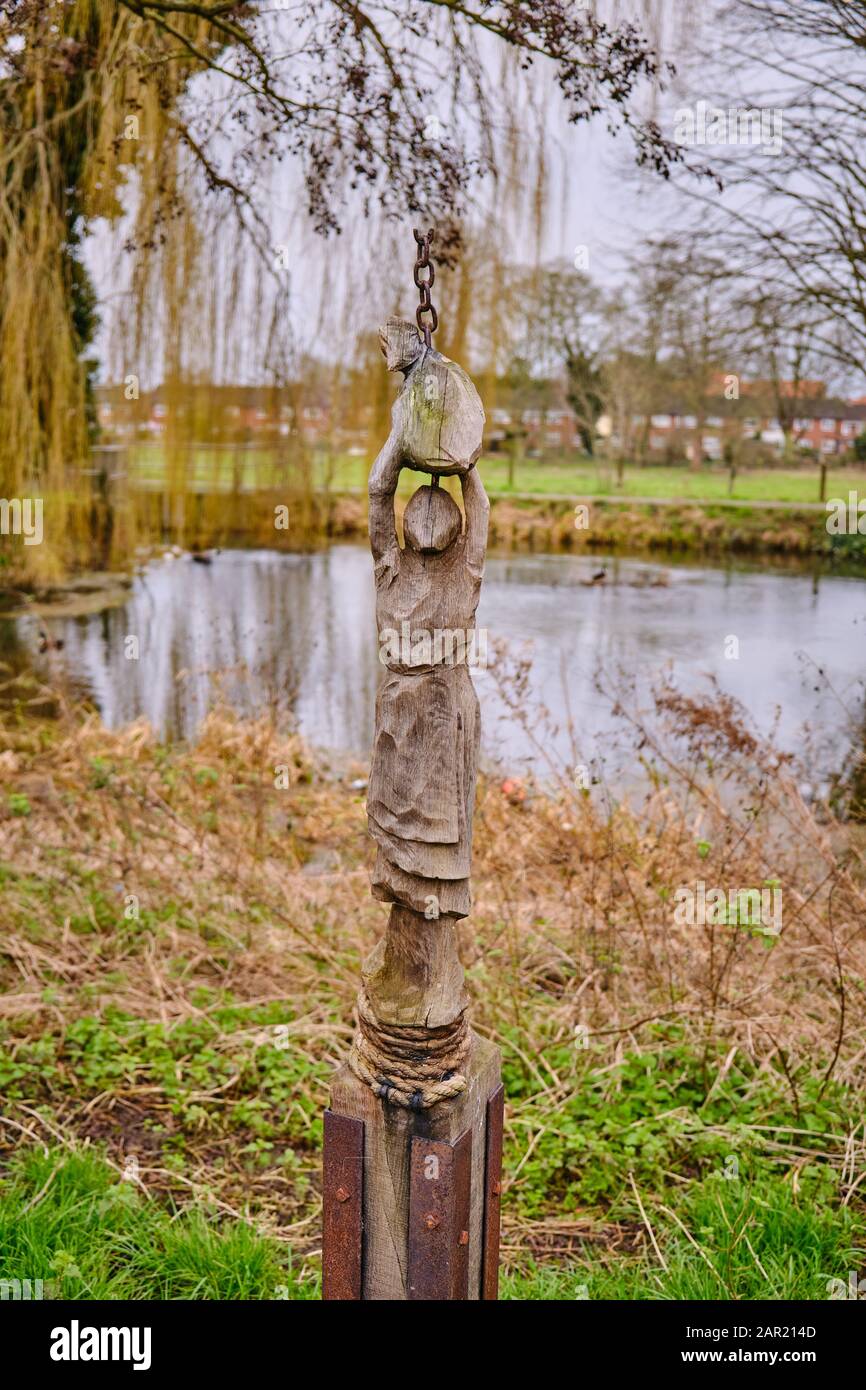 Scultura in legno intagliato figurina di una donna che tiene un sacco di grano sopra la sua testa a lato del fiume slea sleaford Lincolnshire Foto Stock