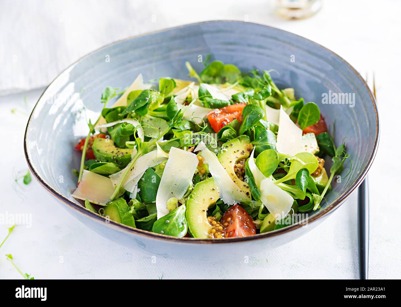 Insalata sana di verdure fresche - pomodori, avocado, insalata di mais, germogli di piselli e semi di chia in ciotola. Menu di dieta Paleo. Foto Stock