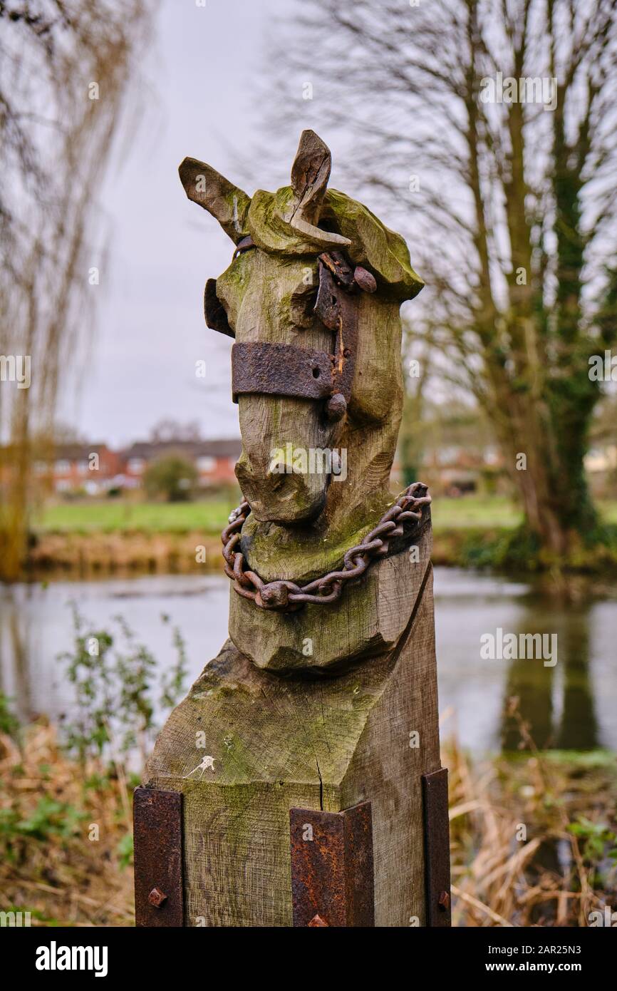 Un'intricata scultura in legno di un cavallo si dirige sulle rive del fiume Slea vicino al mulino Cogglesford a Sleaford con uno sfondo fuori fuoco Foto Stock