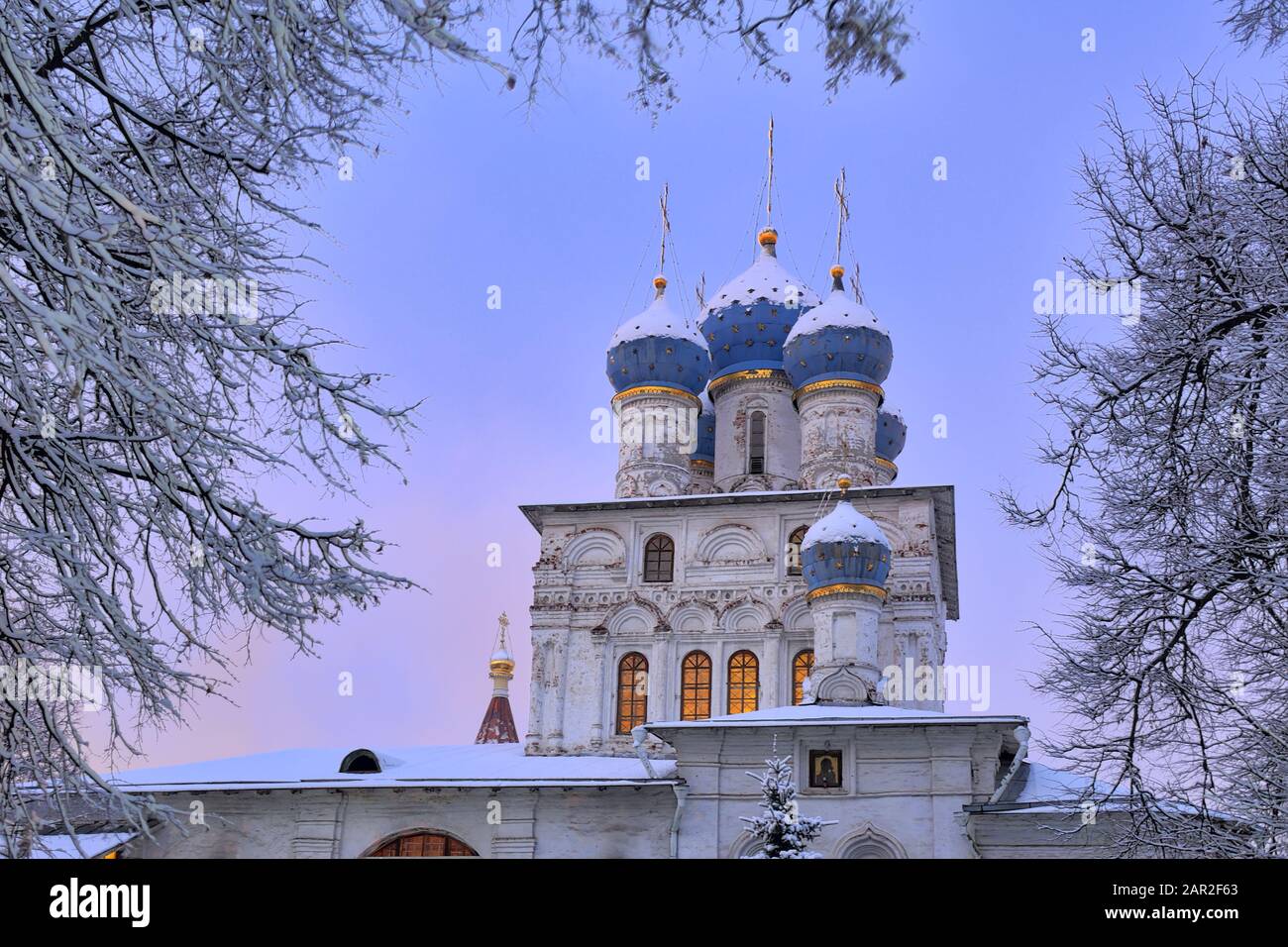 Cupole blu della chiesa di Kazan a Kolomenskoye incorniciata da alberi nel crepuscolo invernale Foto Stock