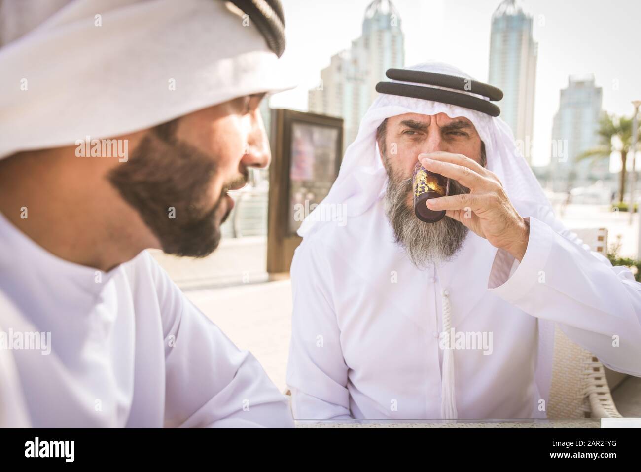 Due uomini d'affari con abiti tradizionali emirates a Dubai - adulti anziani e giovani che hanno affari negli Emirati Arabi Uniti Foto Stock