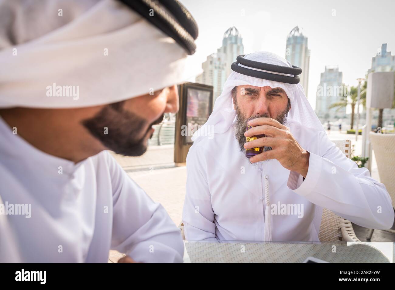 Due uomini d'affari con abiti tradizionali emirates a Dubai - adulti anziani e giovani che hanno affari negli Emirati Arabi Uniti Foto Stock