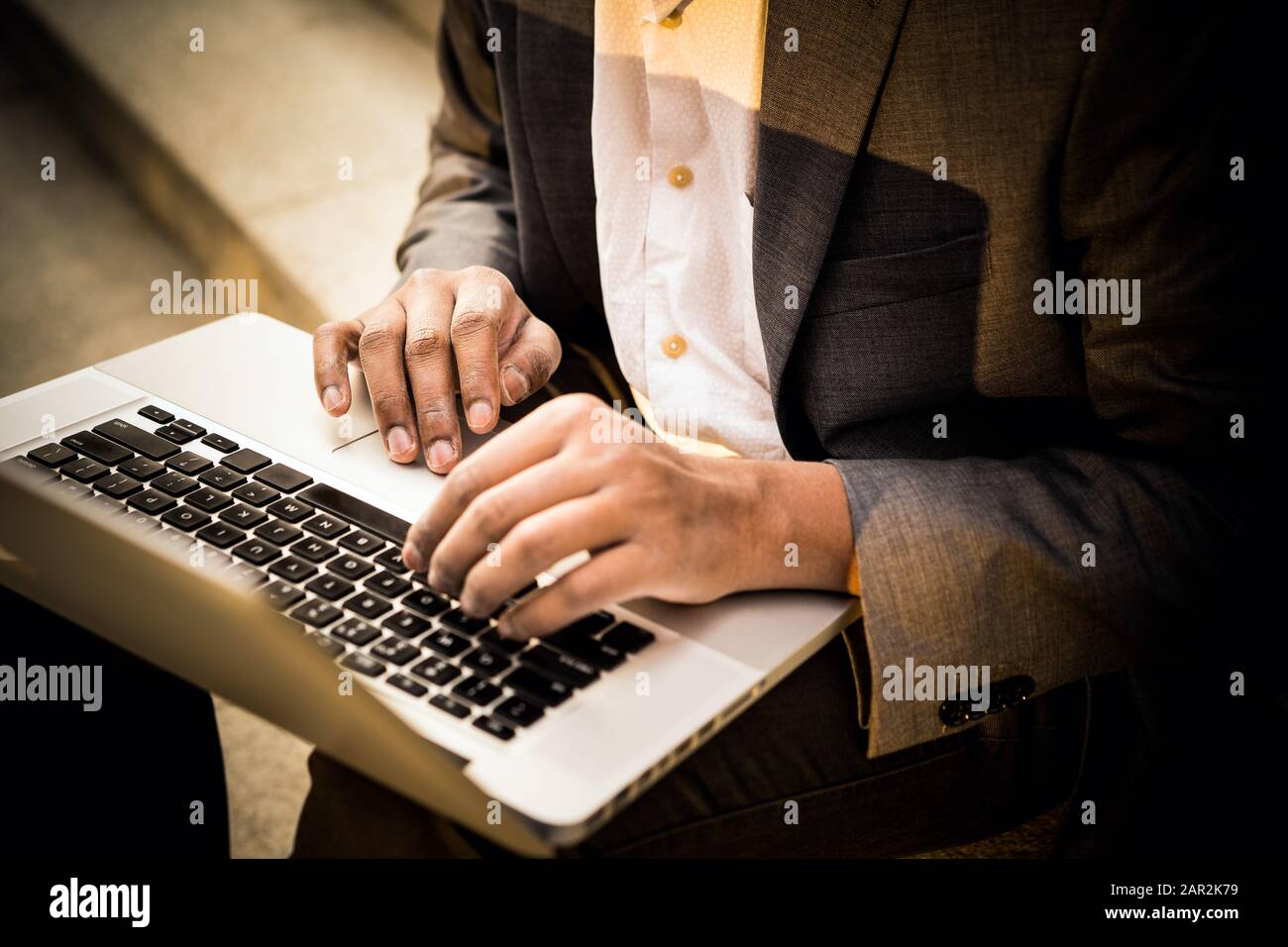 Giovane uomo misto di razza è seduto con un computer portatile, e digitando Foto Stock
