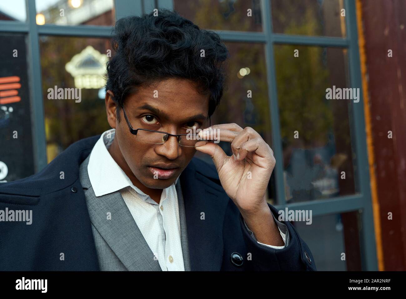 Bel giovane razza mista uomo che guarda oltre i suoi occhiali. Foto Stock