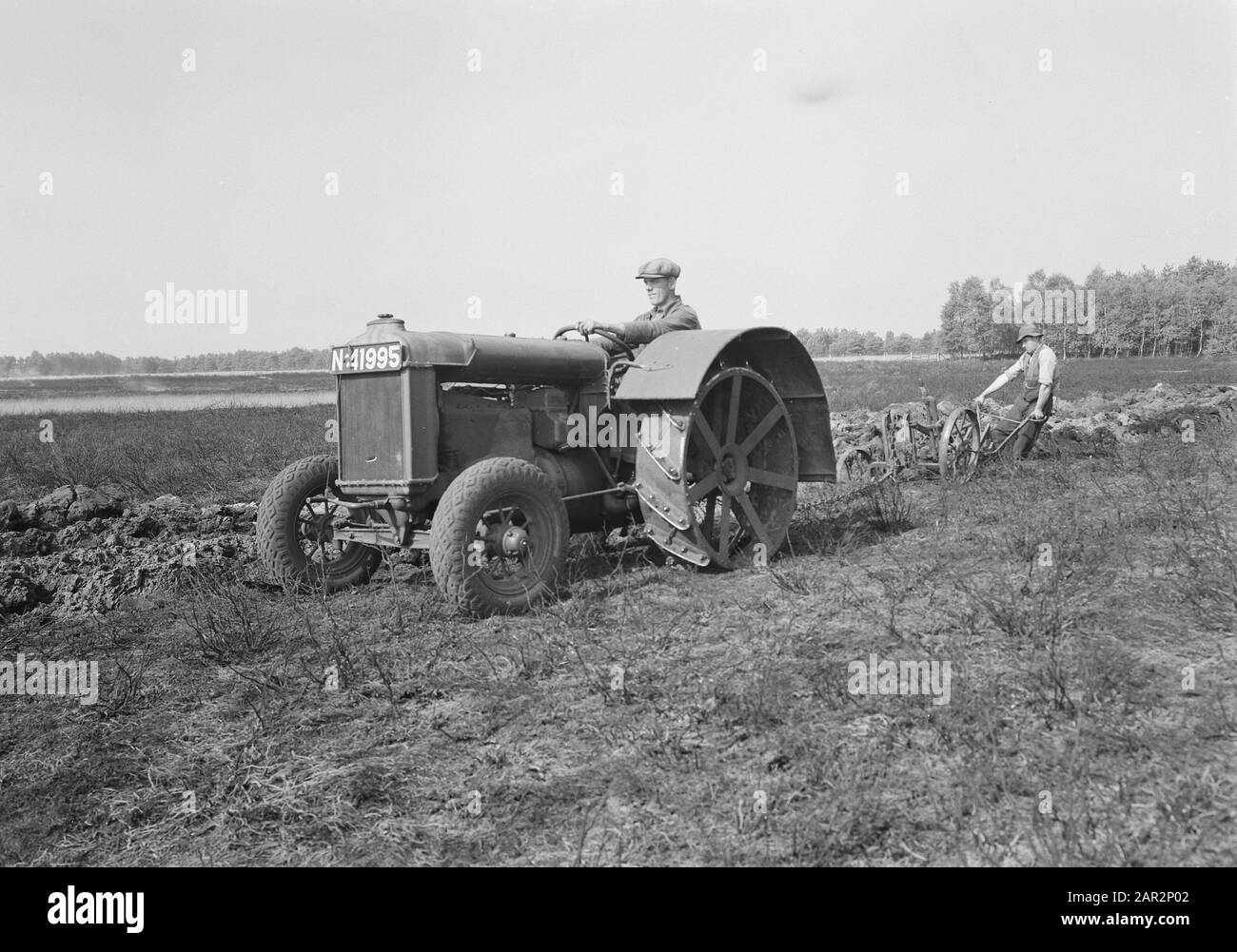 Landgoed De Utrecht. Tractor Fordson Annotation: La proprietà deve il suo nome alla società di assicurazioni sulla vita De Utrecht, Insurance NV. Dal 1898, l'azienda sfruttava le grandi brughiere su larga scala. Il 25 maggio 1899 fu iniziata la prima 700 ettari. Le opere sono state eseguite dall'Heideme. Alla fine, il brughiera fu convertito in 1800 ettari di foresta e 600 ettari di terreno agricolo, mentre 400 ettari di terreno naturale continuarono ad esistere. Data: Parole Chiave non date: Lavoratori, giurati, livellamento, coltivazione, aratura del terreno, estrazione mineraria Foto Stock