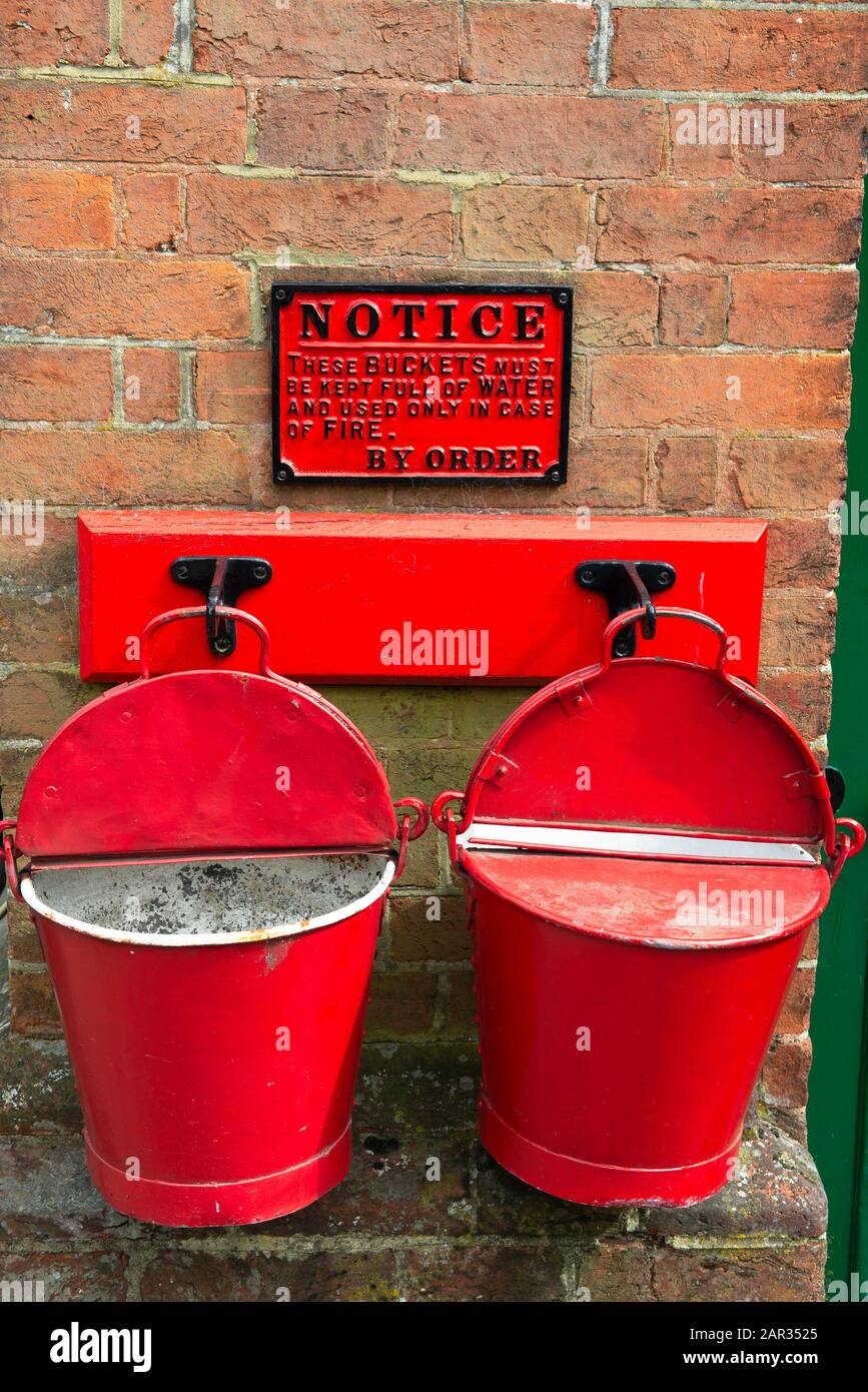 Due secchi d'acqua rosso brillante per l'estinzione presso una stazione restaurata sulla Bluebell Line, West Sussex, Regno Unito Foto Stock