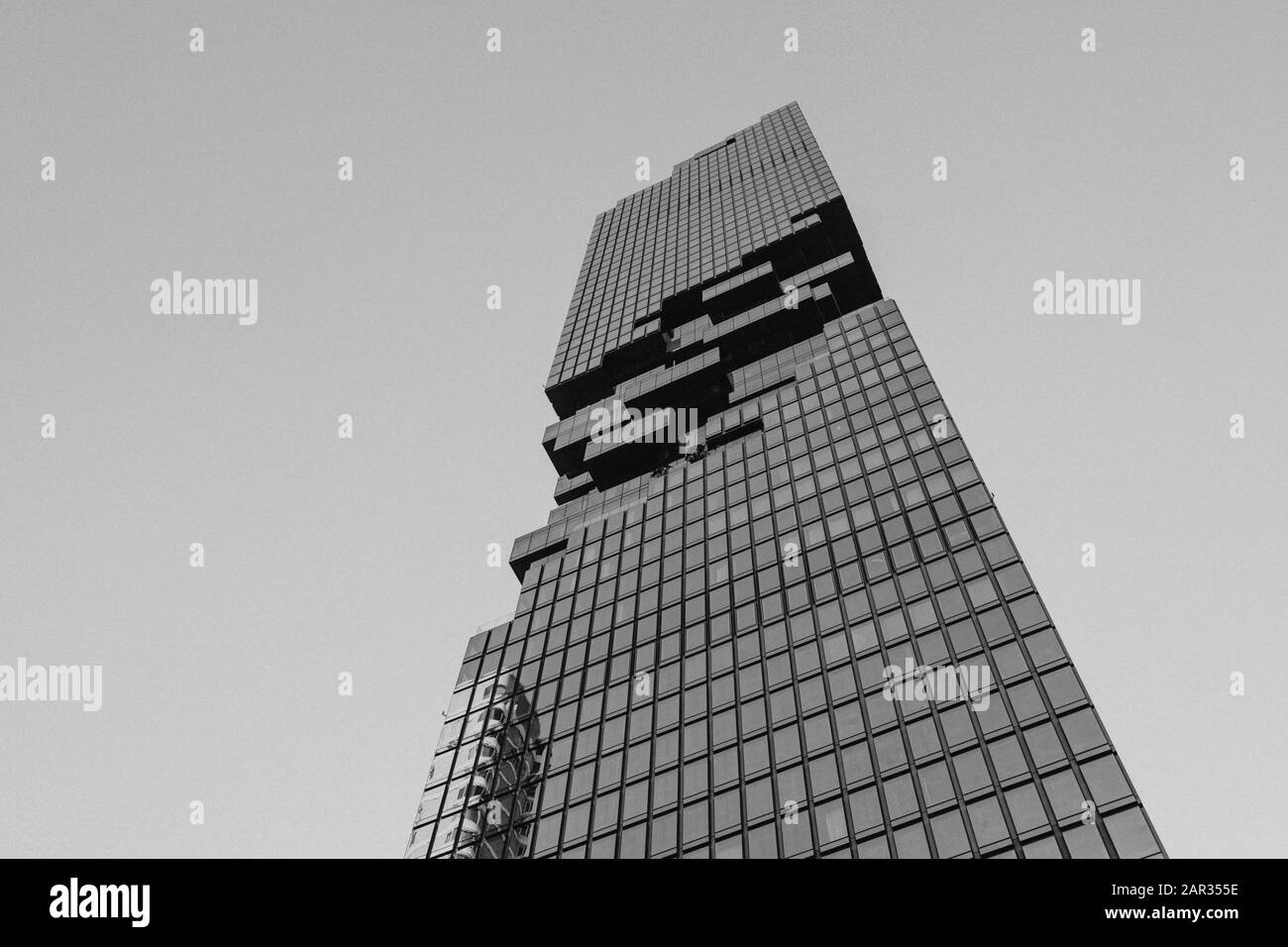 Tono bianco e nero, vista ad angolo basso di King Power Mahanakhon, moderna torre di uso mix progettato da Ole Scheeren il grattacielo più alto di Bangkok. Foto Stock