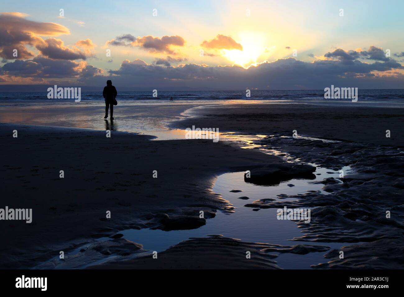 Persona a piedi sulla spiaggia a Dunraven Bay al tramonto, vicino Southerndown, South Glamorgan, Galles, Regno Unito Foto Stock