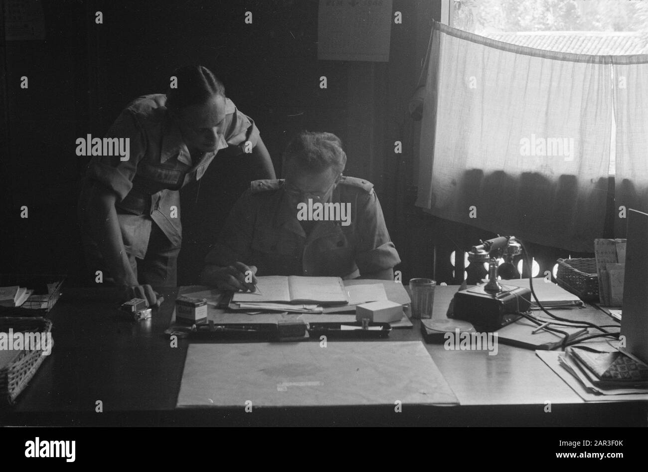 4th Brigata di fanteria pronta per marzo a Wlingi Due soldati, il cui posto è un secondo tenente) si piegano su carte su una scrivania in un ufficio Data : Dicembre 1948 luogo: Indonesia, Indie orientali olandesi Foto Stock