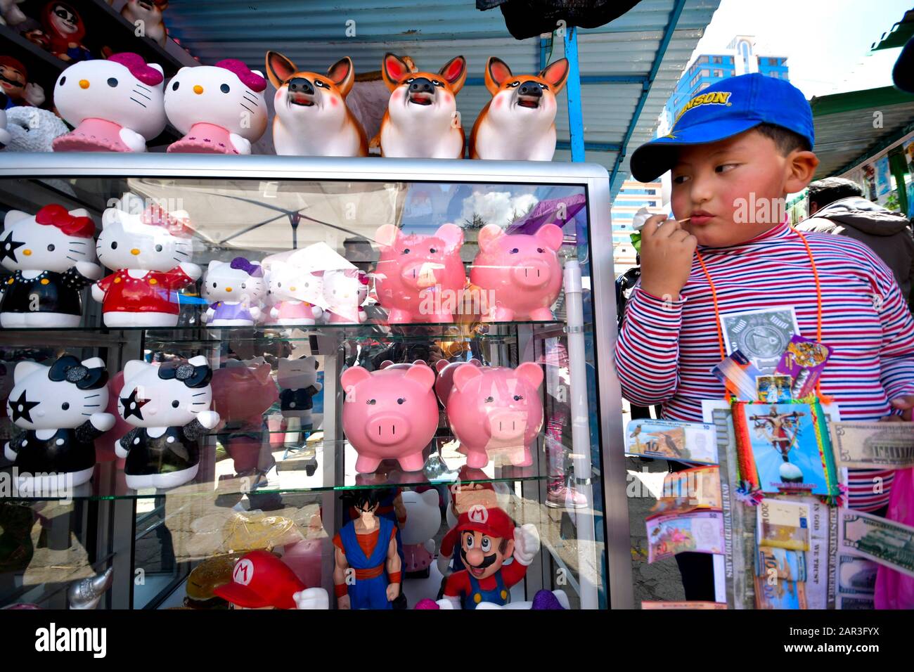 La Paz, Bolivia. 22nd Gen 2020. Un ragazzo controlla alcuni maiali guardiani in Bolivia Alausitas prosperità festival a la Paz. Là, la gente compra che cosa vorrebbero avere durante l'anno o da esso per la gente, come in un 'mercato di desiderio '. Tutto è basato generalmente sulle mniature delle cose che la gente desidera. Il più comon è quello di acquistare denaro falso, come American Dolards, pesos Bolivianos o anche euro. Credit: Christian Lombardi/Zuma Wire/Alamy Live News Foto Stock