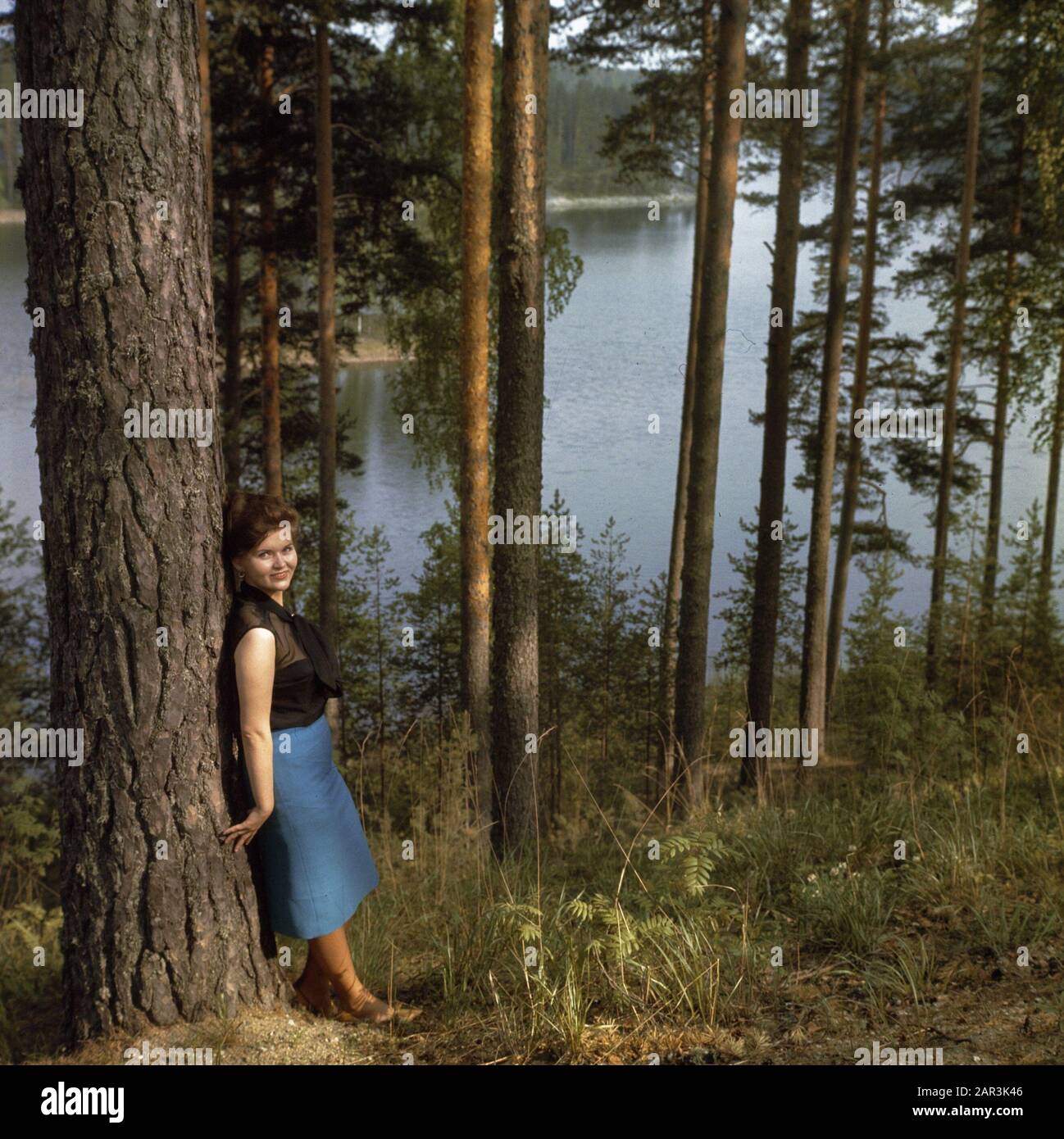 Donna appoggiata contro un albero Data: Non data Foto Stock