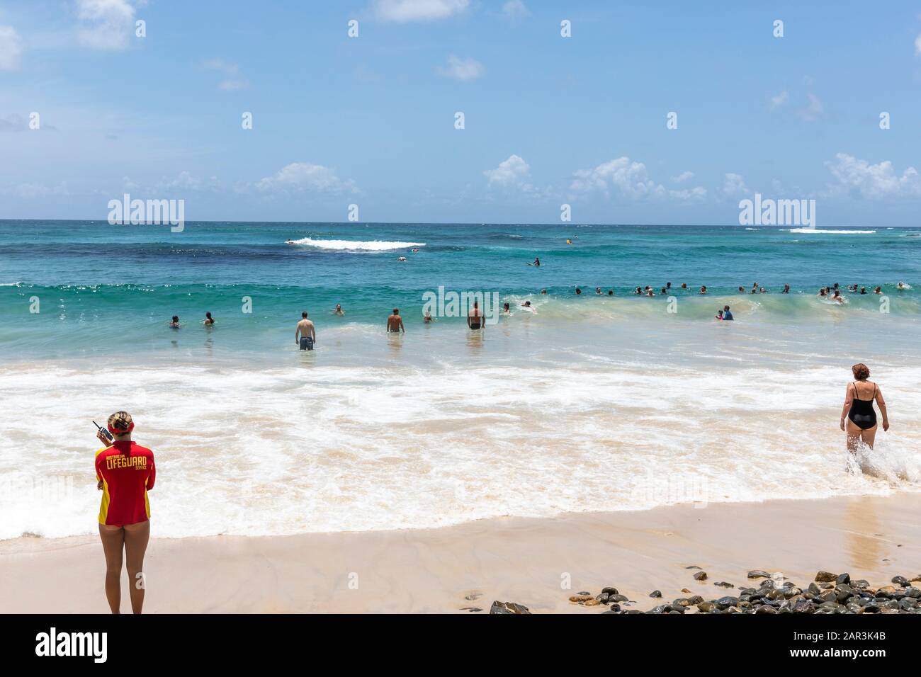 Bagnino femminile a Byron Bay wategos spiaggia guarda persone che nuotano nell'oceano, nuovo Galles del Sud, Australia Foto Stock