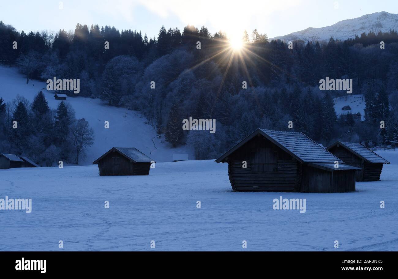 Garmisch Partenkirchen, Germania. 23rd Gen 2020. Il sole sorge dietro un tipico paesaggio culturale del Werdenfelserland. I paesaggi culturali con i loro 'prati alpini e prealpini e paesaggi di brughiera' sono stati sulla cosiddetta lista provvisoria da alcuni anni. Gli attivisti per il benessere degli animali criticano il fatto che, in relazione a un’applicazione del Patrimonio Mondiale dell’Umanità dell’alta Baviera, il controverso tethering è classificato come degno di essere preservato. Credito: Angelika Warmuth/Dpa/Alamy Live News Foto Stock