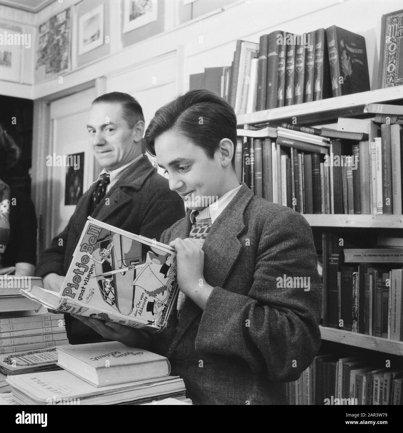 Finanza: Purificazione del denaro riduzioni di prezzo a causa della ristrutturazione del denaro, libreria Annotazioni: Ragazzo Guarda il libro Pieje Bell sta per volare da Fr. Van Abkoude Data: 1945 Parole Chiave: Finanza, riduzioni di prezzo Foto Stock