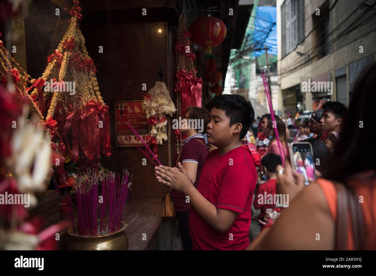 Manila, Filippine. 25th Gen 2020. I filippini pregano con i bastoni di incenso davanti ad un altare cattolico ibrido durante la celebrazione.Migliaia di filippini celebrano il nuovo anno lunare nel distretto di Chinatown di Manila il 25 gennaio, nonostante la minaccia di un coronavirus mortale che è emerso a Wuhan, Cina il mese scorso. la chinatown di Manila è considerata la più antica del mondo, essendo stata fondata nel 1594. Credit: Sopa Images Limited/Alamy Live News Foto Stock