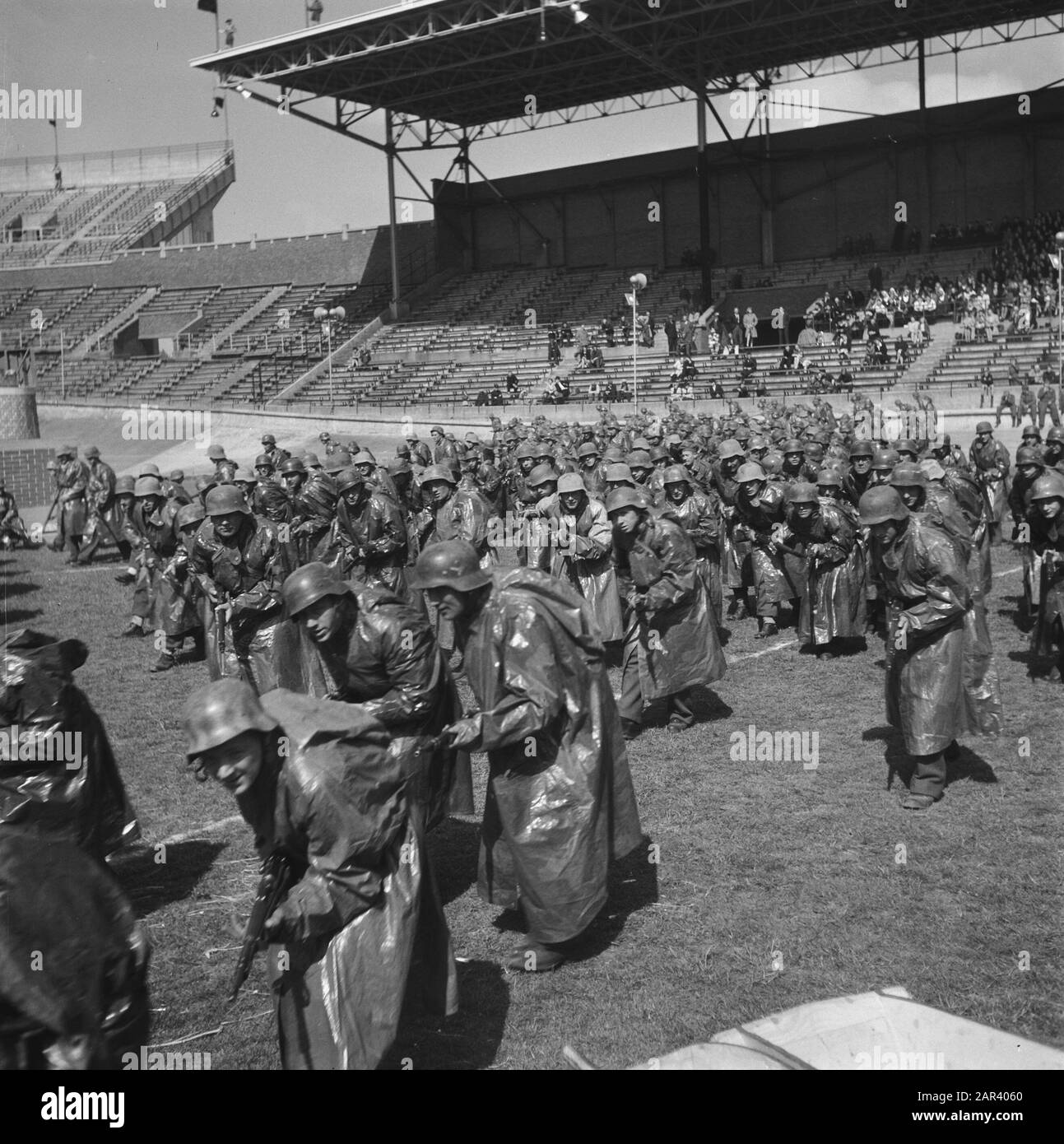 Prove generali per il gioco della Liberazione, che si terranno il 4 e 6 maggio 1946 alle prove generali dello Stadio Olimpico per il gioco della Liberazione, che si terranno il 4 e 6 maggio 1946 nello Stadio Olimpico di Amsterdam Annotazione: Gruppo di soldati tedeschi in impermeabili Data: 3 maggio 1946 luogo: Amsterdam Parole Chiave: Teatro all'aperto, prove Nome dell'istituzione: Stadio Olimpico Foto Stock