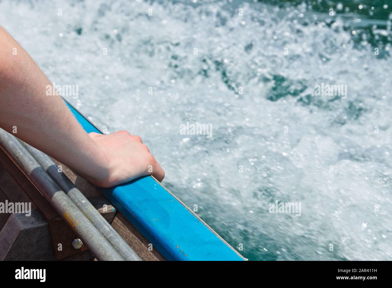 Primo piano di una persona che mette la mano sul nave al mare Foto Stock