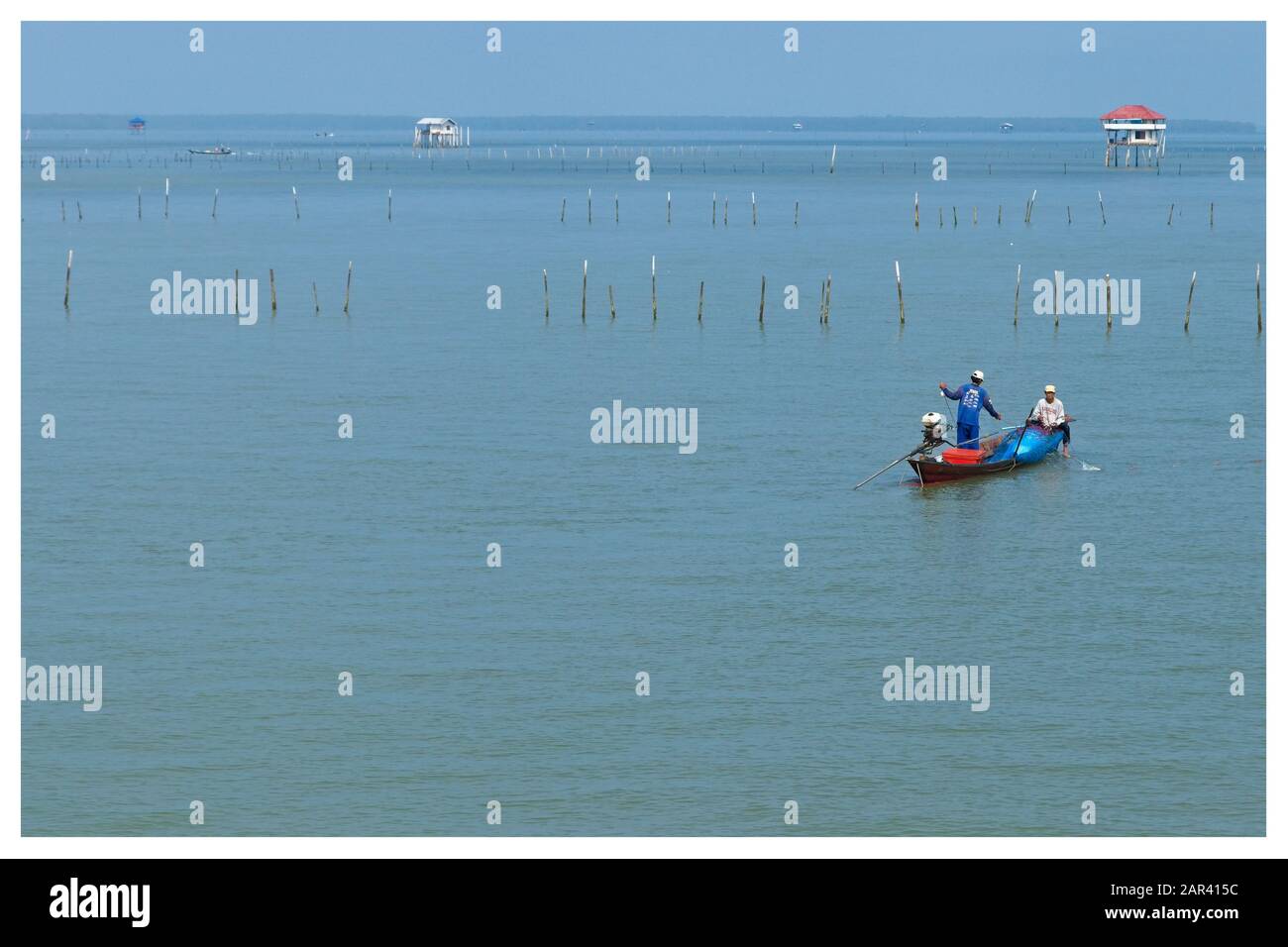 Surat Thani, THAILANDIA - 18 marzo 2019: Due pescatori che pescano da una tradizionale barca a coda lunga vicino al porto di Surat Thani in Thailandia. Foto Stock