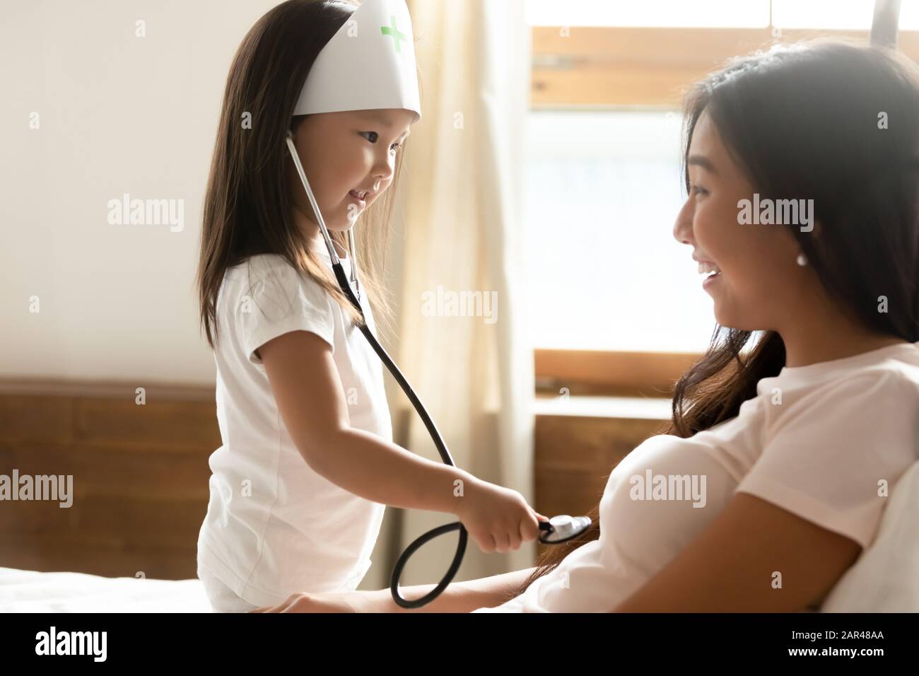 Bambina asiatica gioca medico con mamma giovane Foto Stock