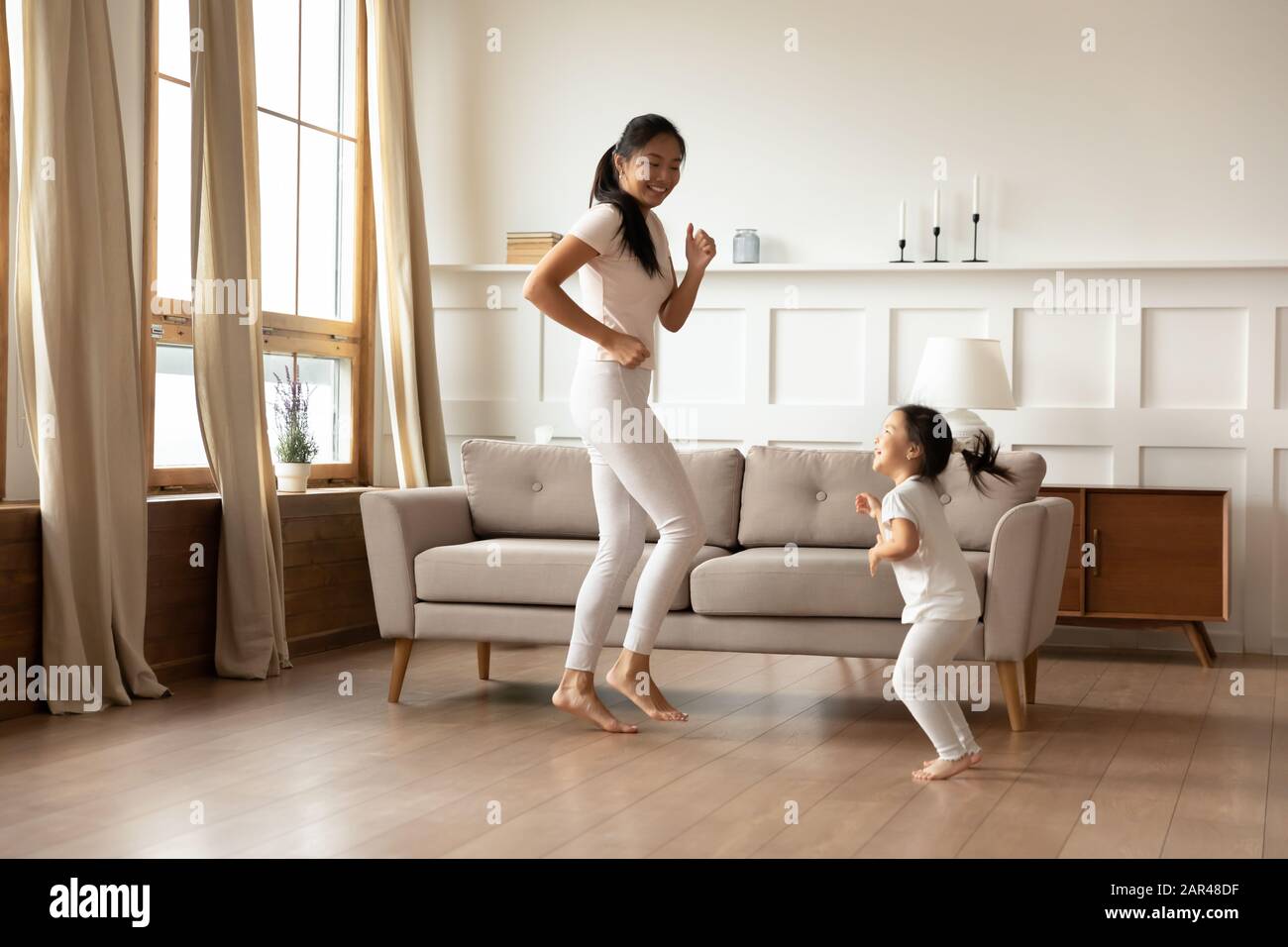 Felice mamma asiatica e figlia che ballano a casa Foto Stock